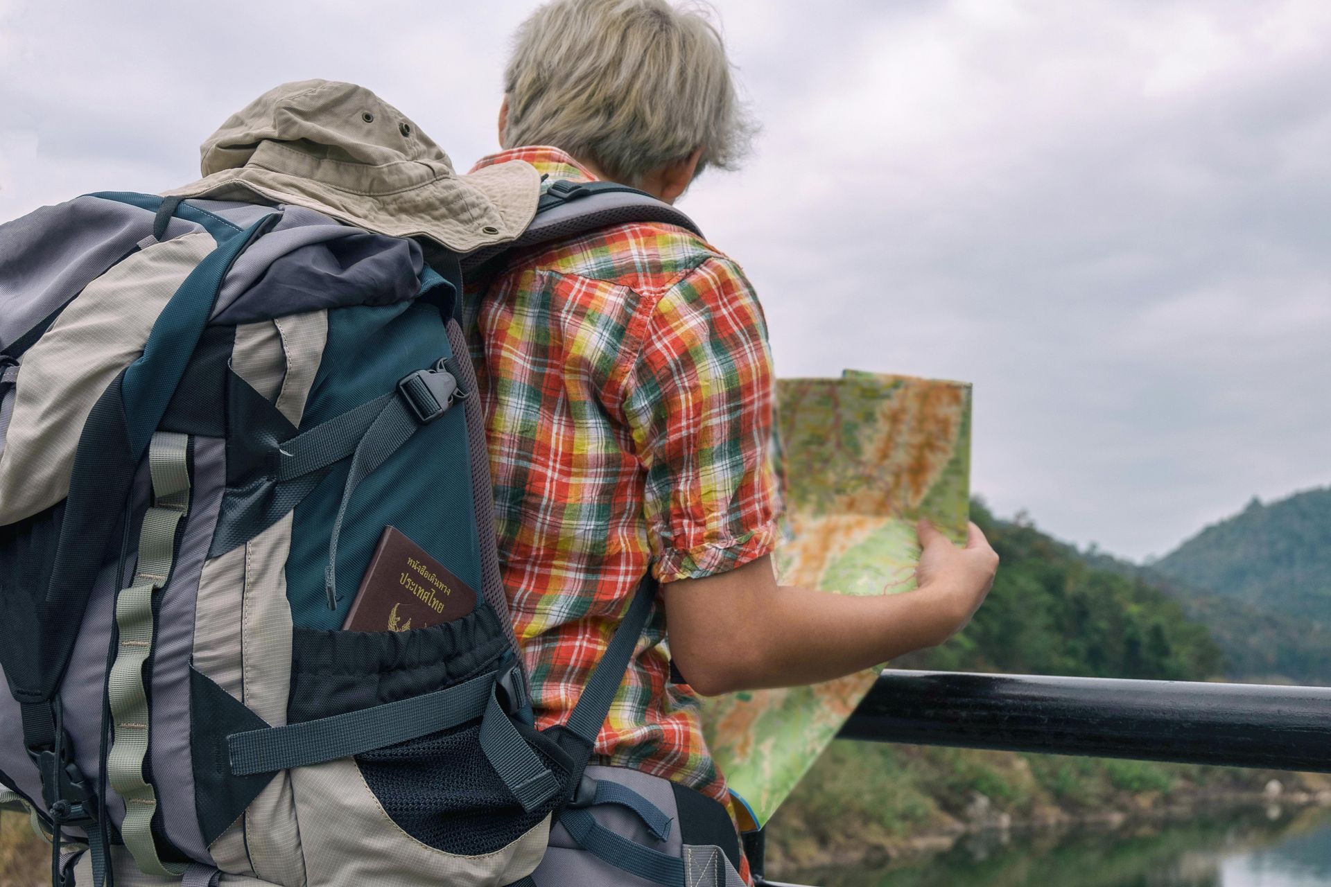 Person reading a map outdoors and carrying backpacking bag