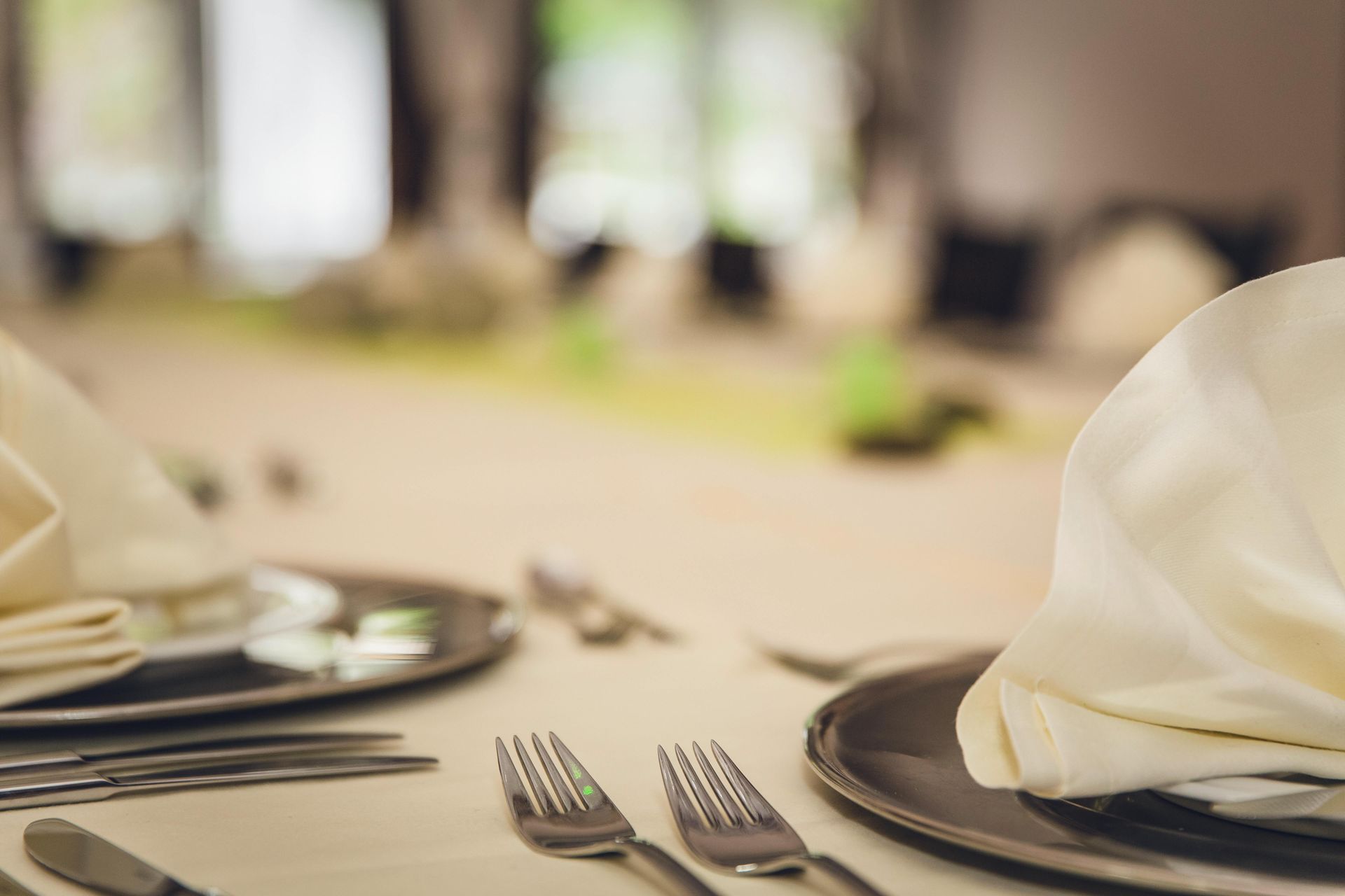 Formal dining table set with silverware, plates, and white napkins prepared for a meal.