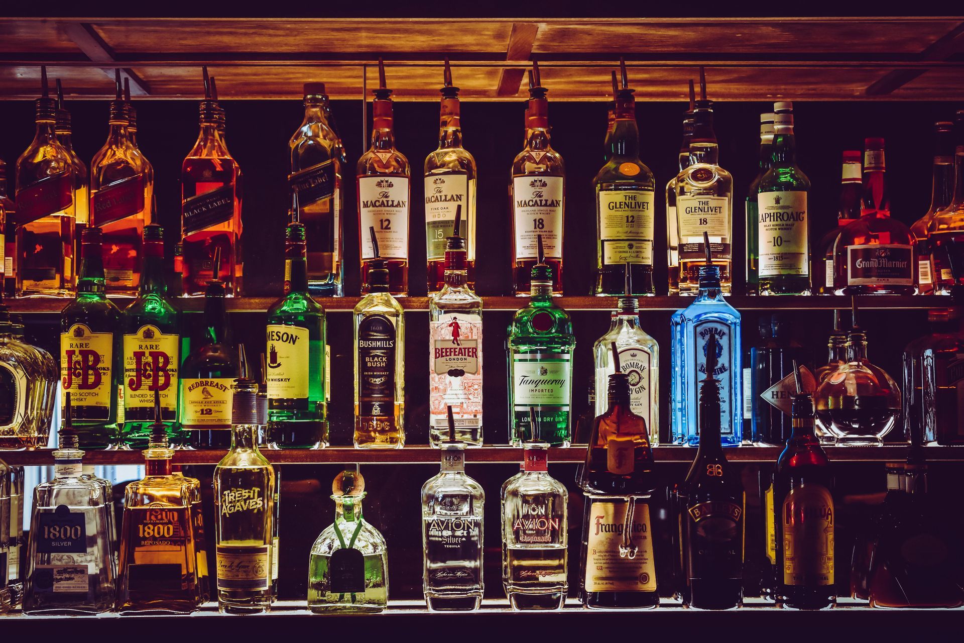 Display of different colored glass alcohol bottles at a bar