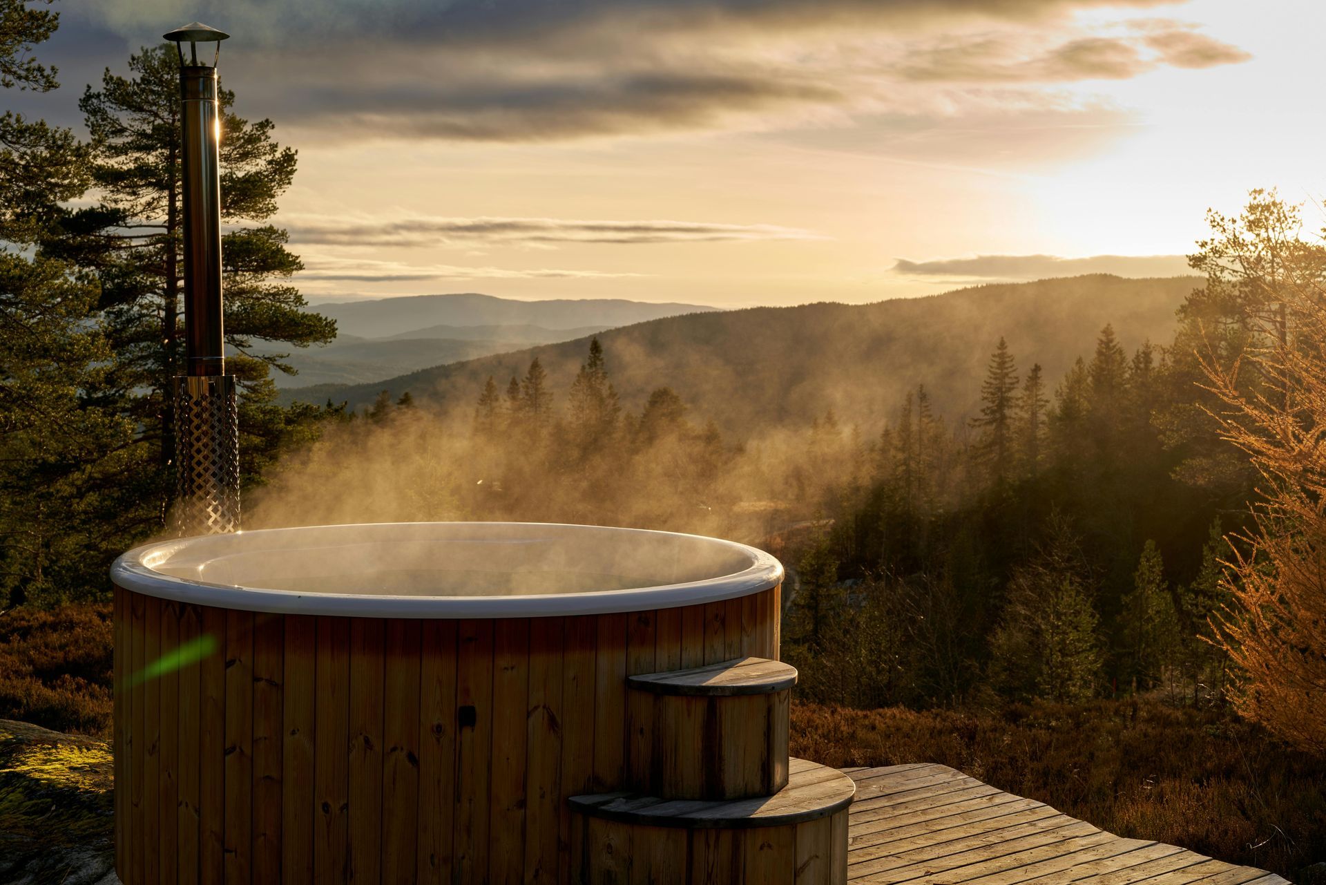 Steaming hot tub sitting on hill with beautiful mountain overlook during sunset