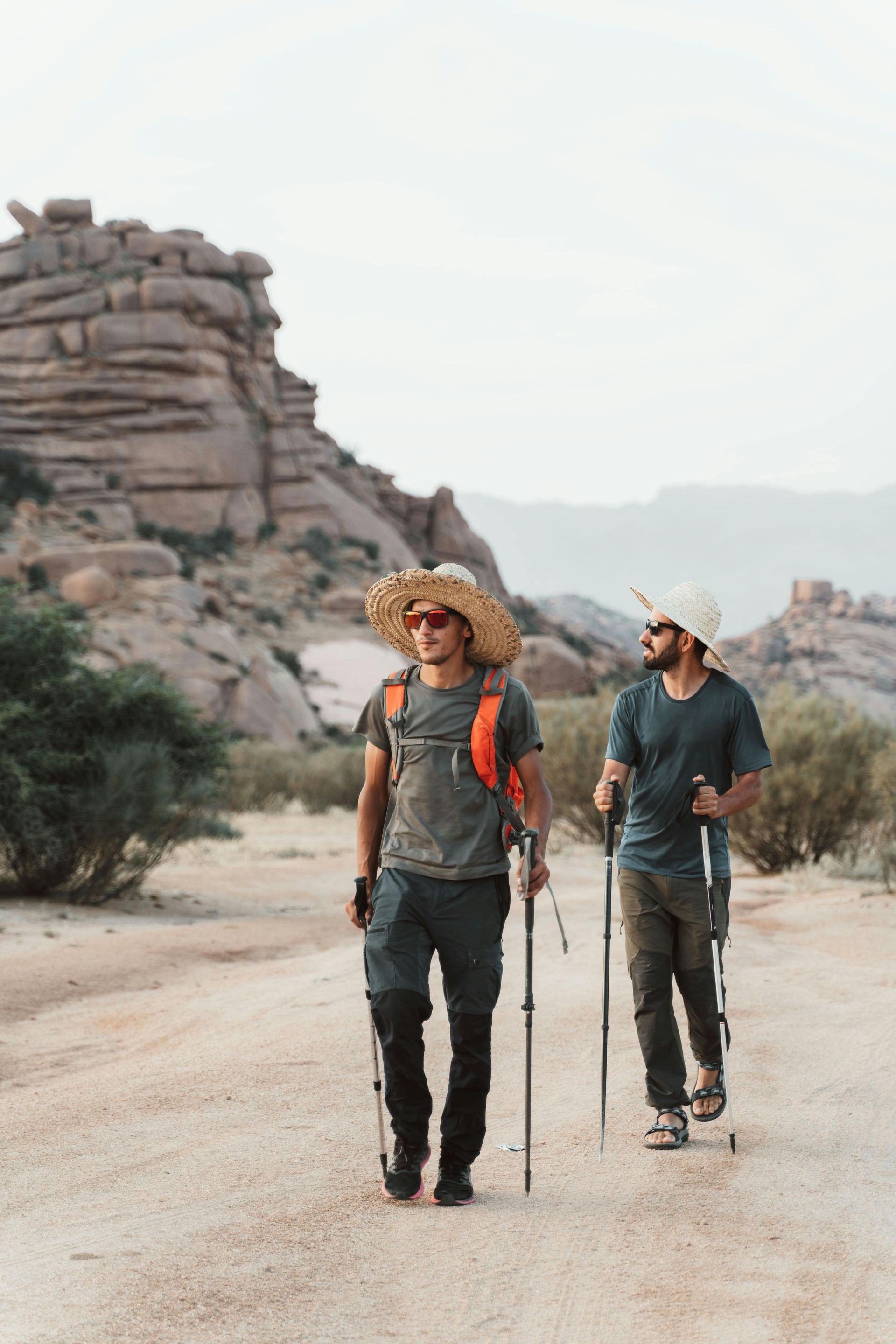 Men hiking outdoors with proper sun shading hat, sunglasses and hiking poles