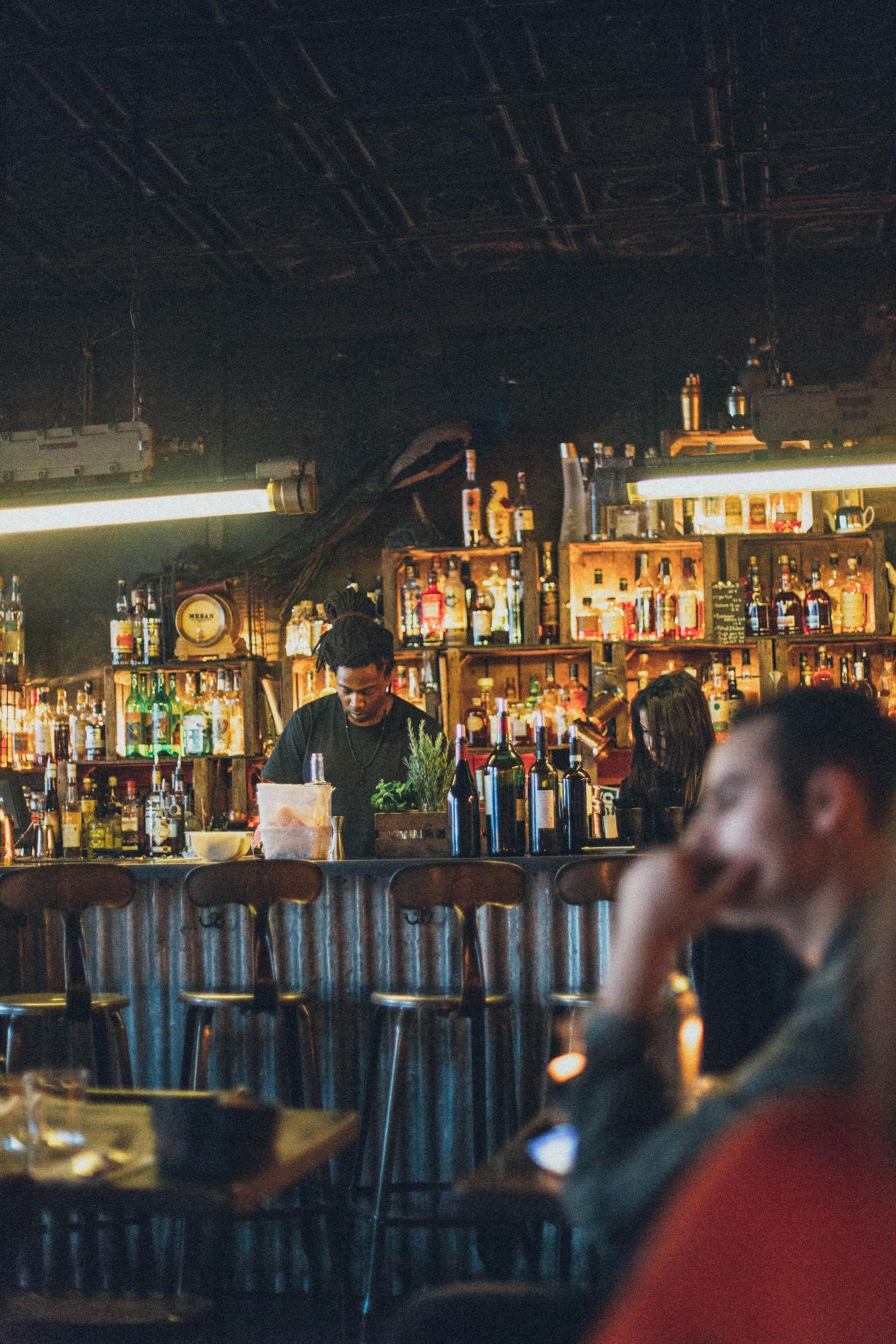 Bartender at a spacious bar preparing drinks for patrons
