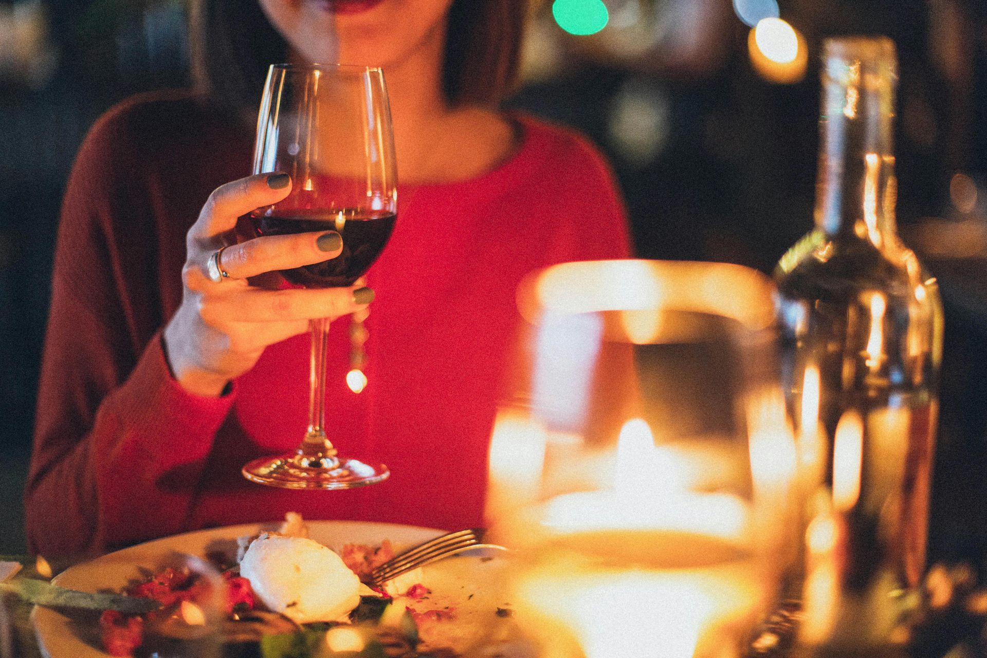 A woman enjoying a glass of wine by candlelight at a restaurant