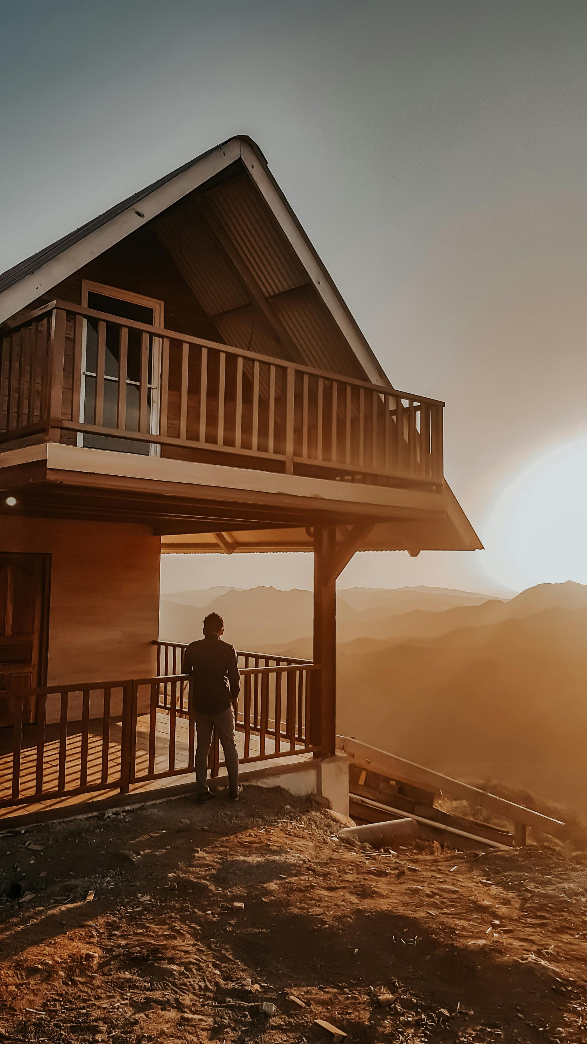 Person standing on a cabin deck overlooking a golden wilderness landscape