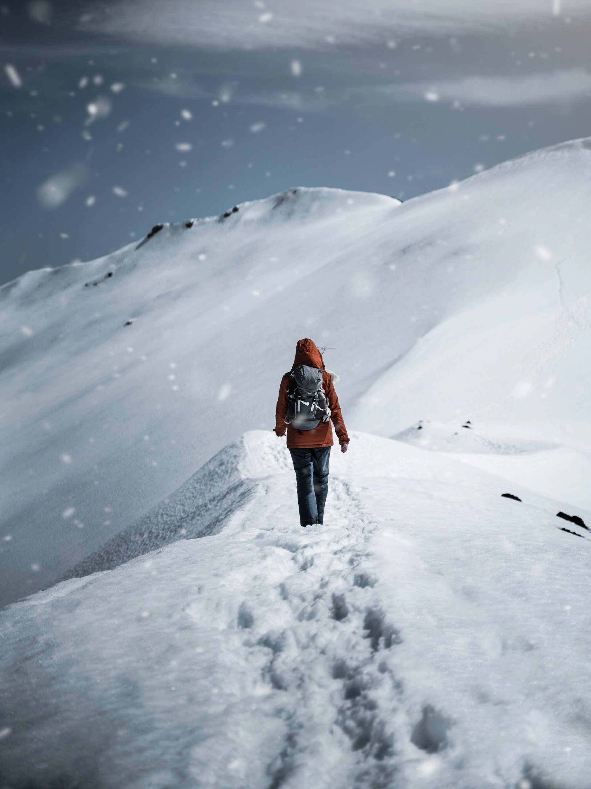 Person walking in the snowy hills carrying a backpack