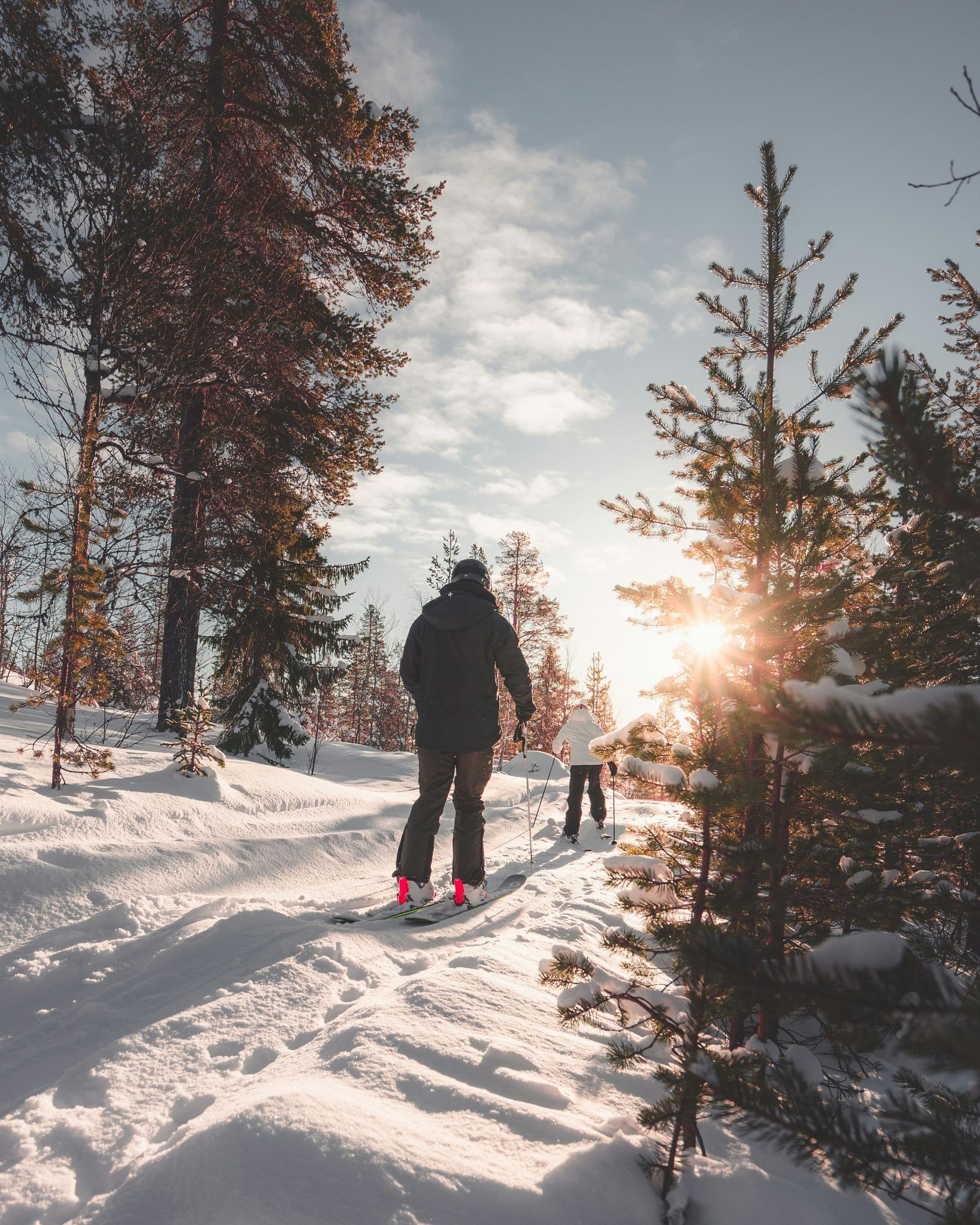 Couple snowshoeing outdoors through pine trees on a sunny day