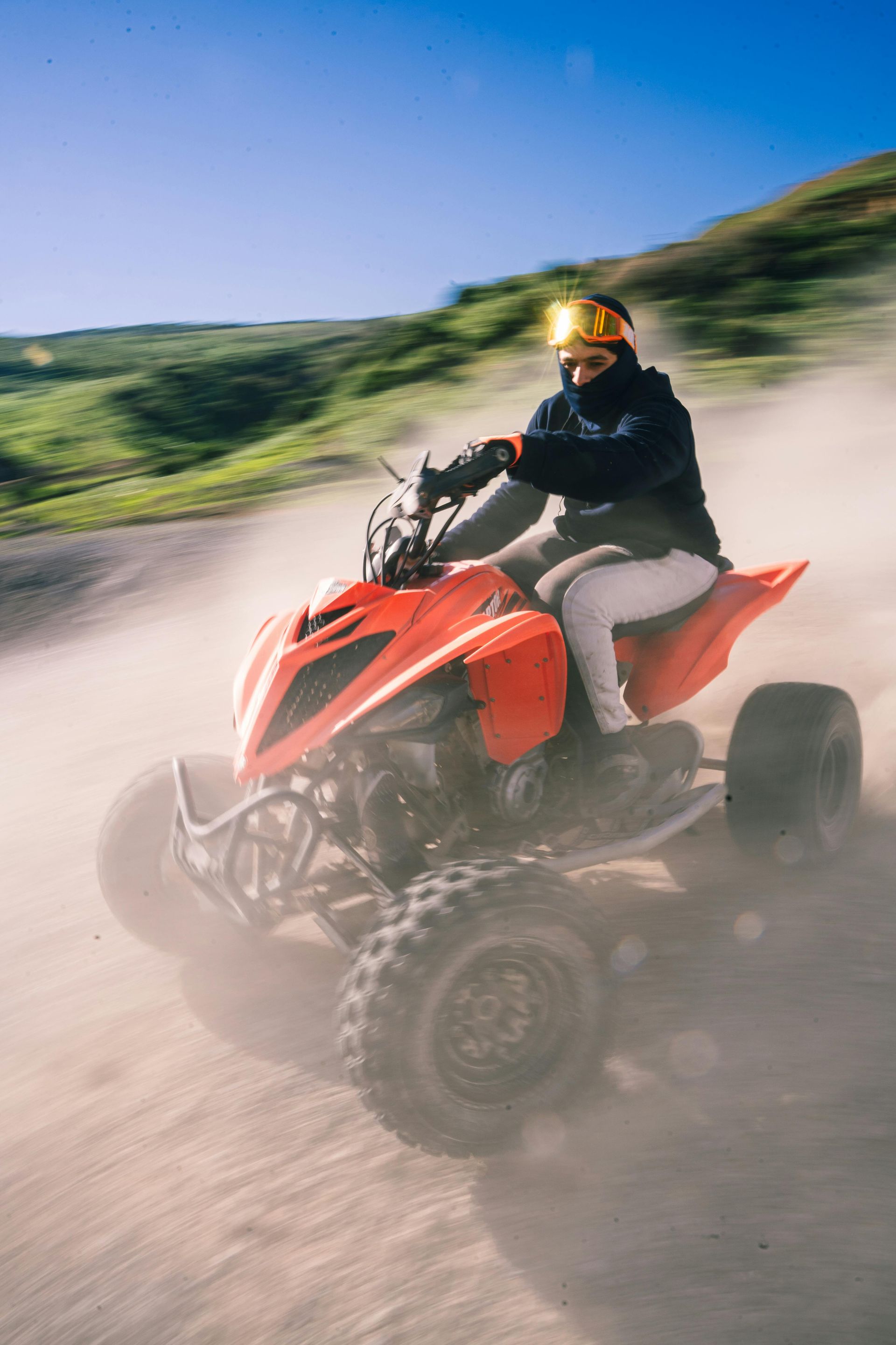 Person speeding through the dirt on ATV with lush green grass nearby