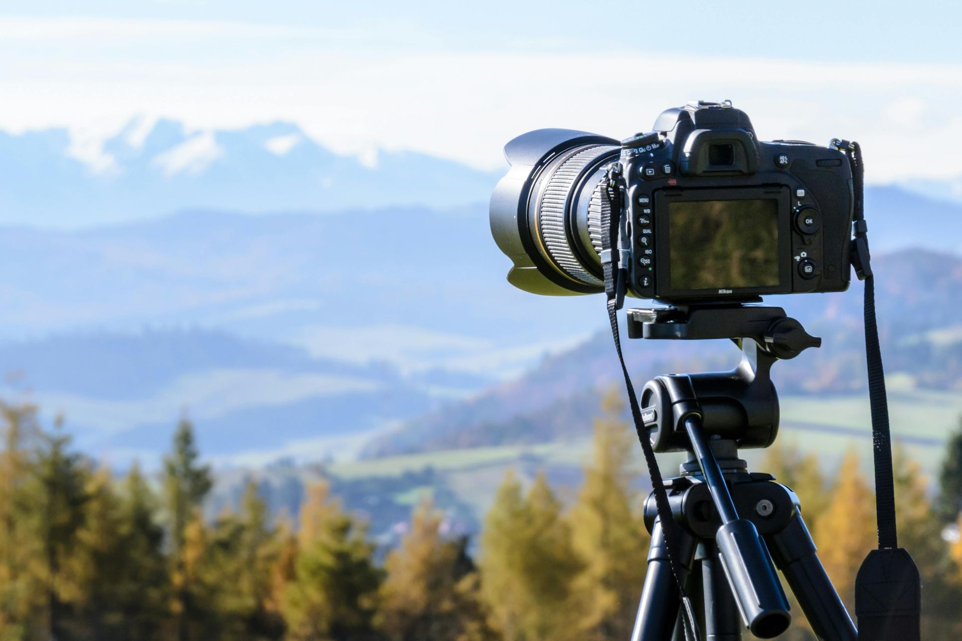 Camera set up on tripod looking out over  pine trees and mountains