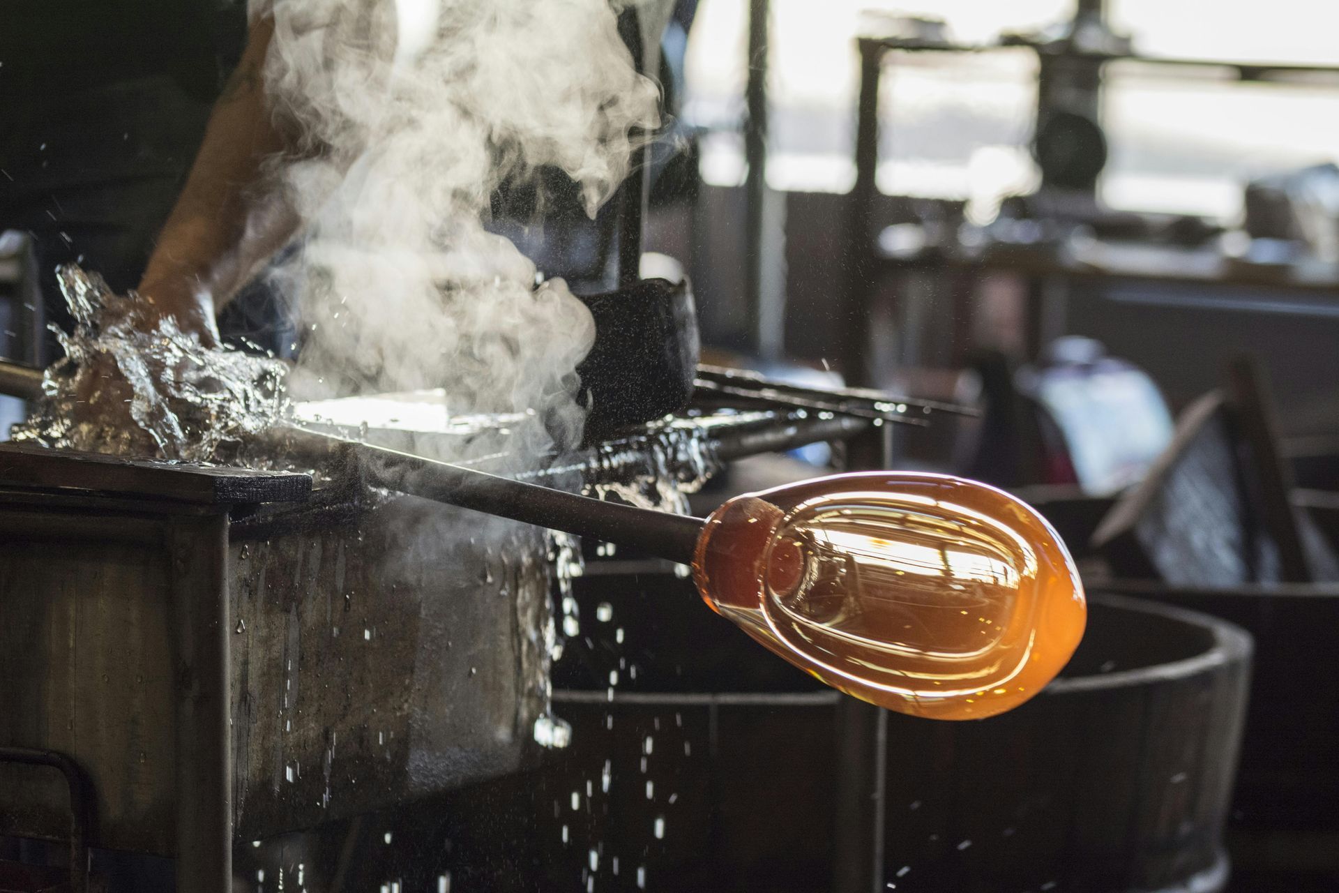 Person working with hot glass making unique blown glass pieces