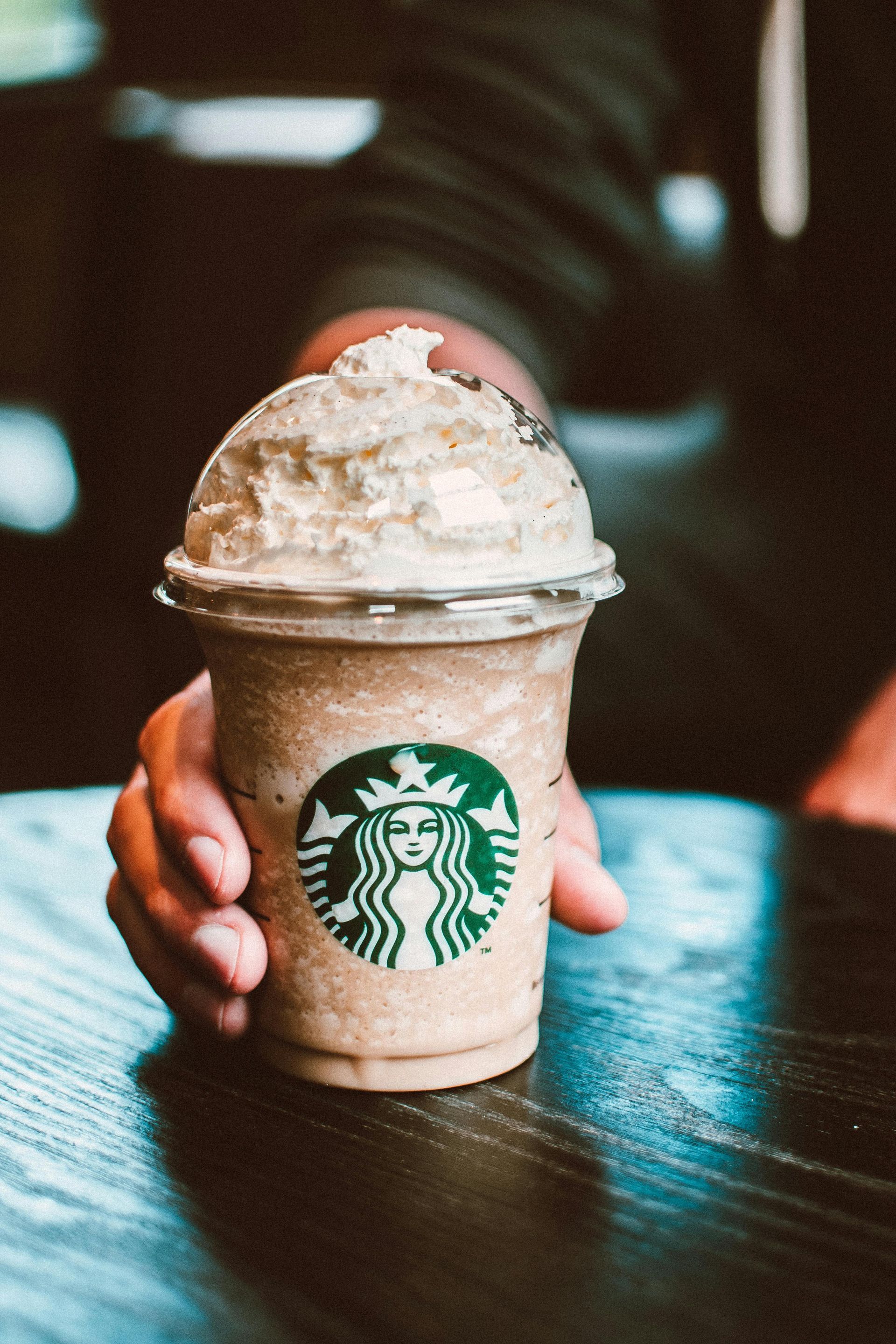 Starbucks drink in a plastic cup with whipped cream on top