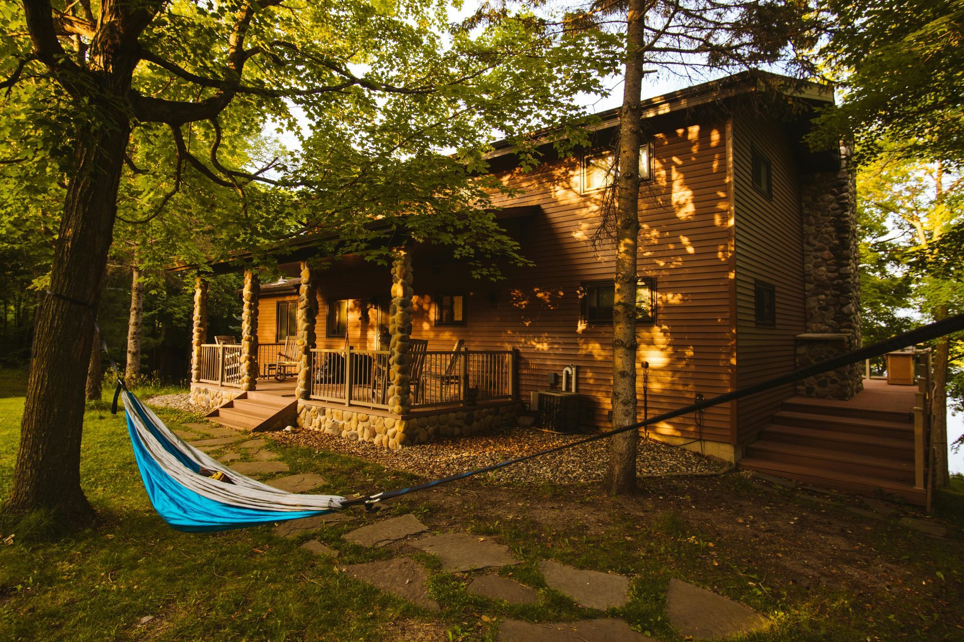 Medium wooden cabin nestled among trees with a hammock hanging in nearby trees