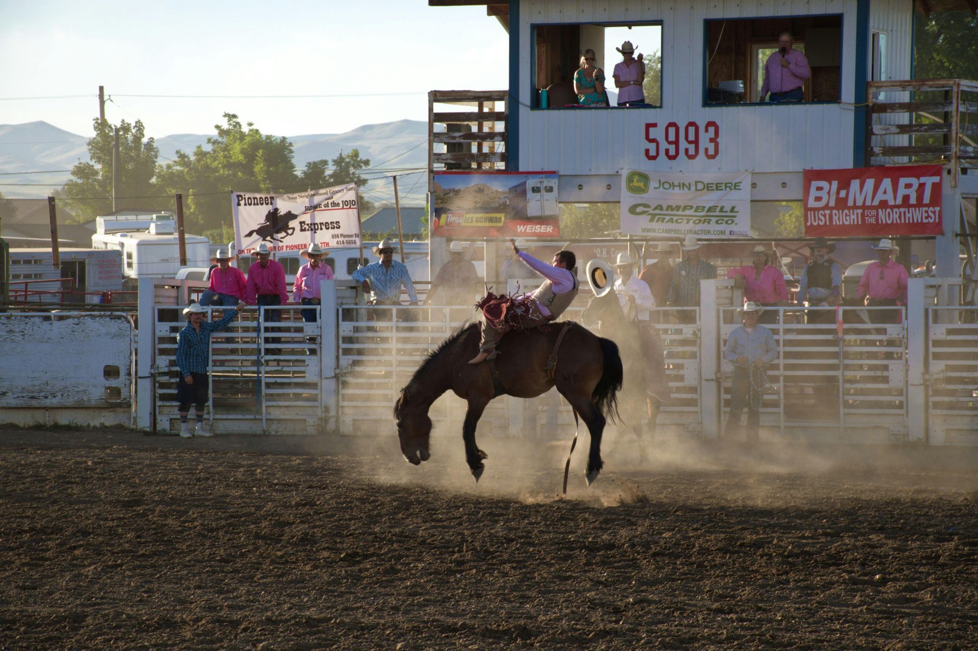 Person riding horse at rodeo with an audience and kicking up dirt
