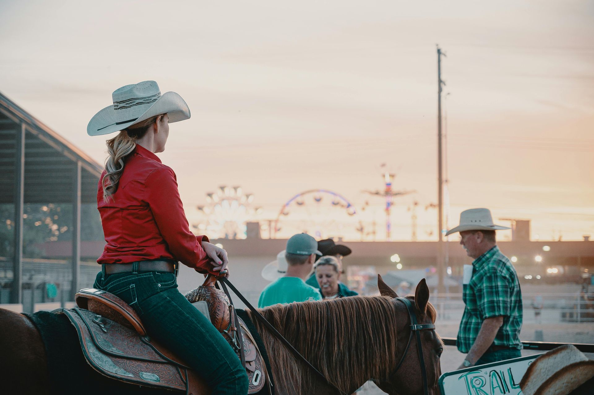 Woman wearing a cowboy hat riding a horse in small crowd