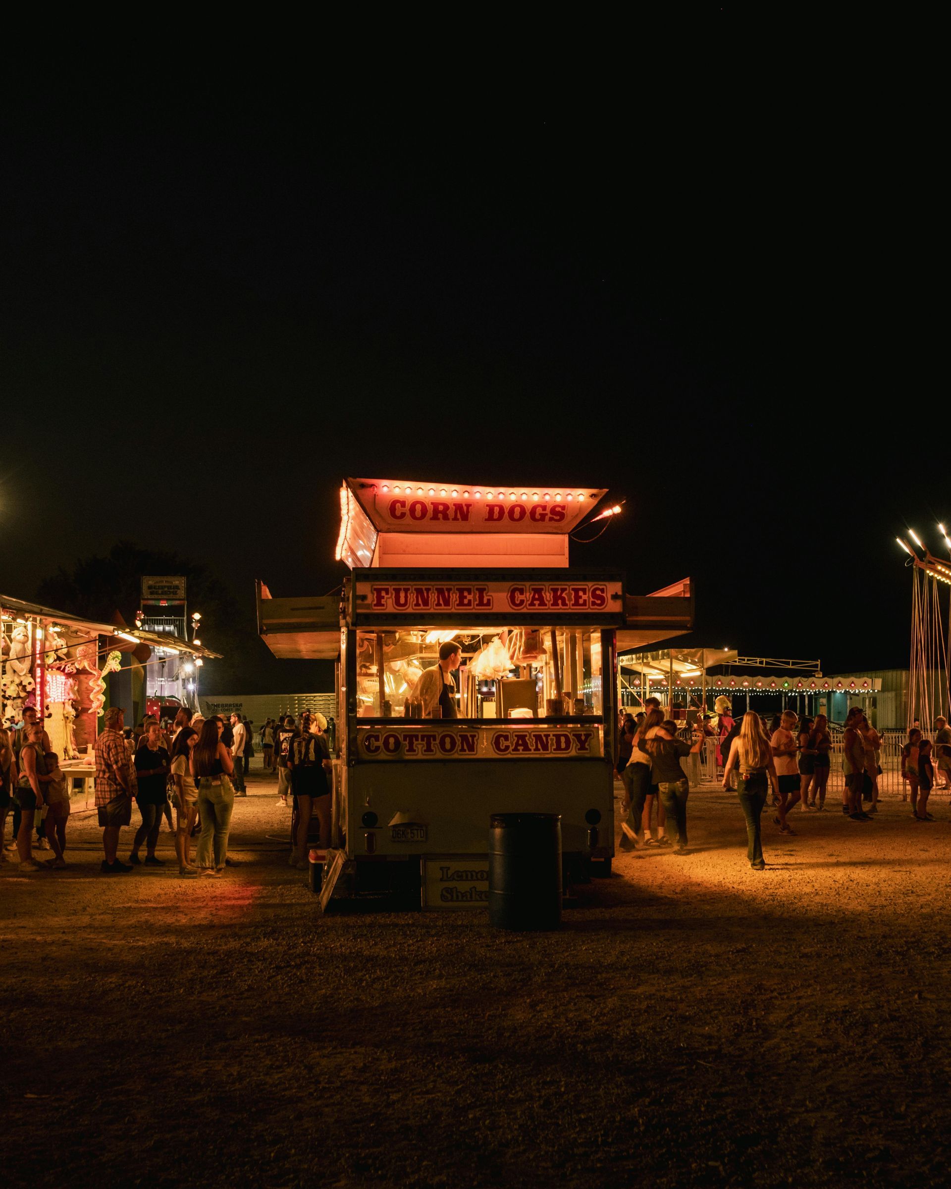 Food stand at outdoor carnival surrounded by people