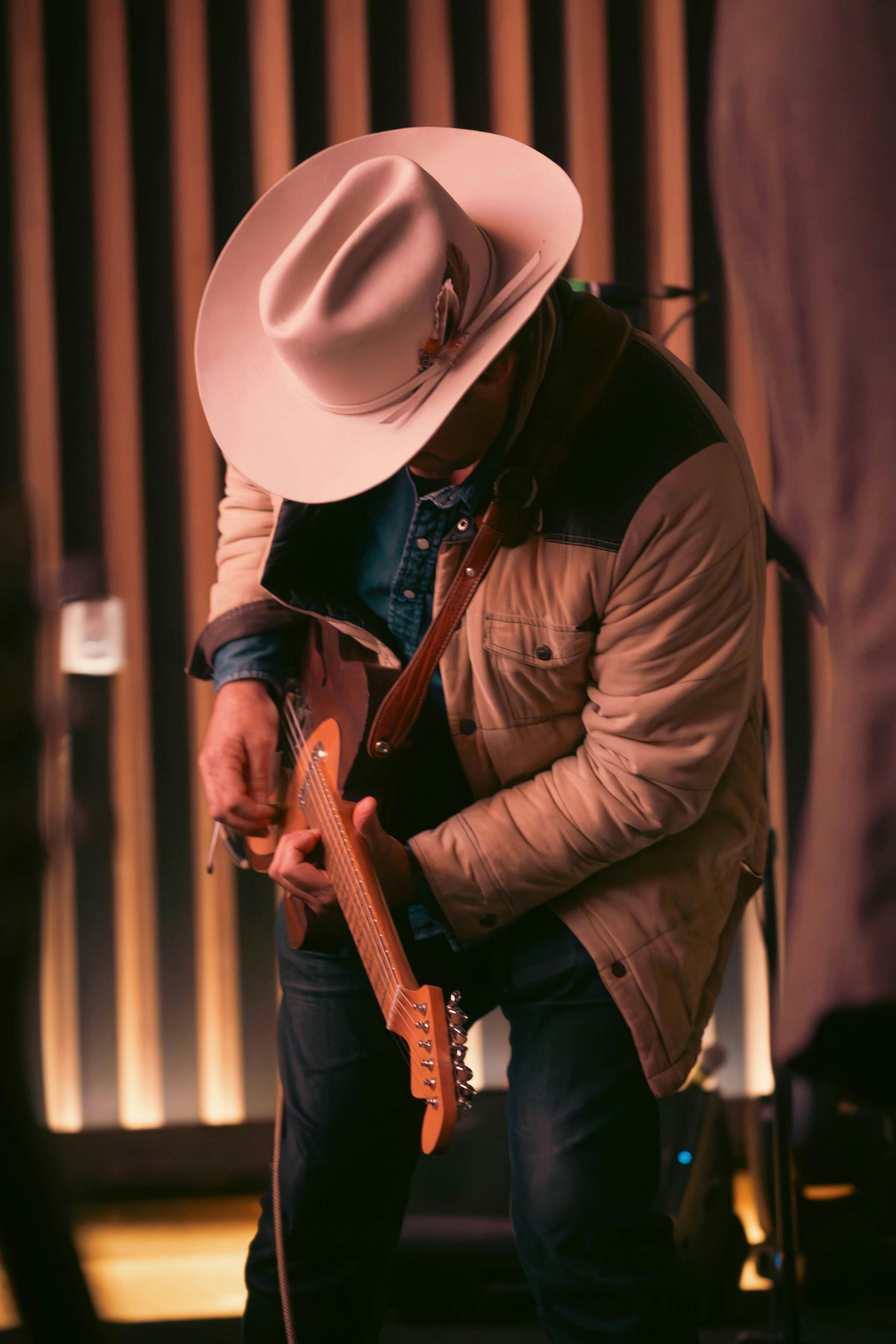 Person in cowboy hat playing guitar for live music 