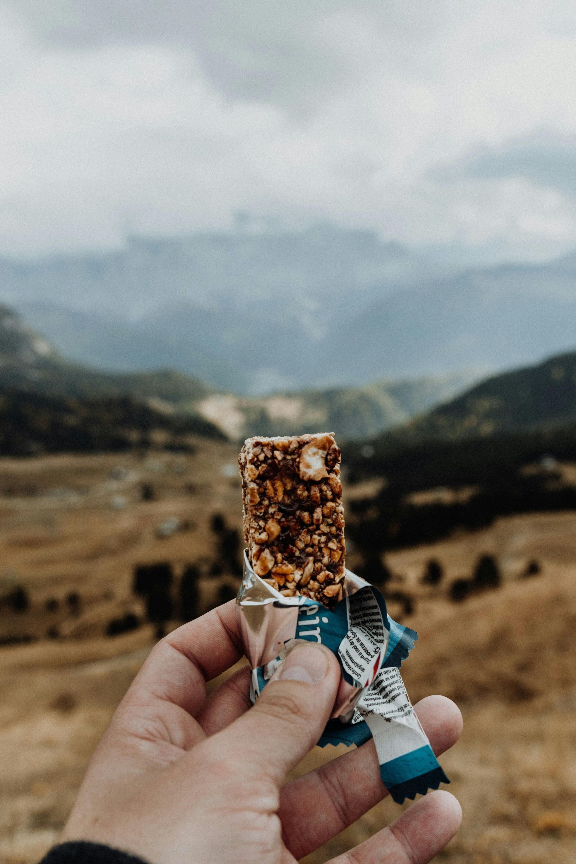Someone holding a nutrition bar while out on the trails