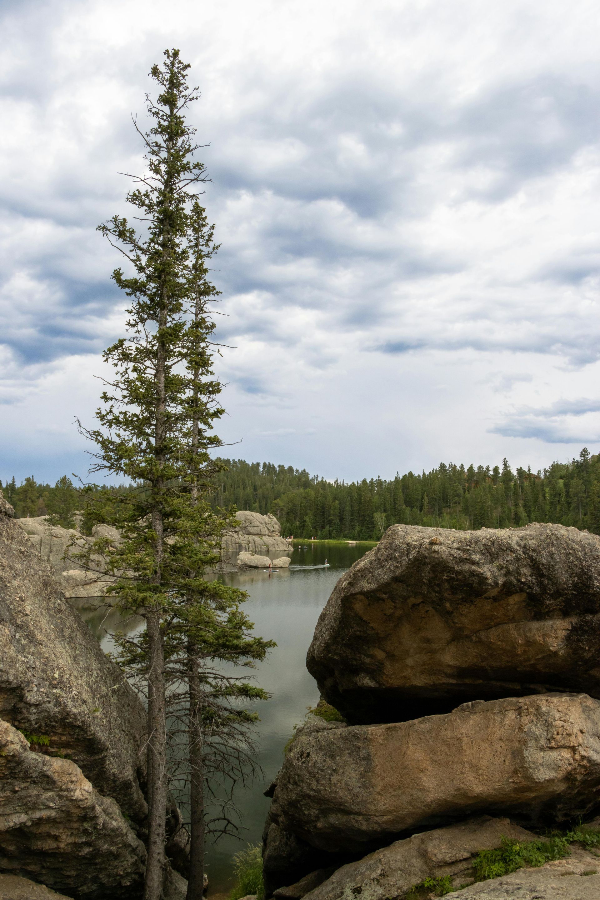 View of lake surrounded by large boulders and pine trees