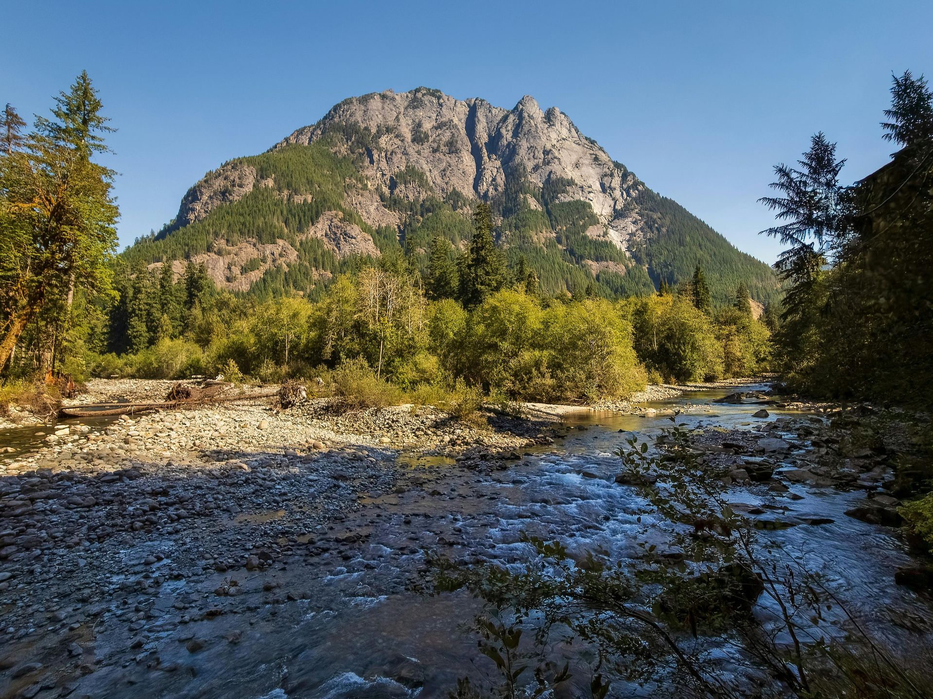 Large rock hill, surrounded by trees and shallow, small creek running through the rock trail