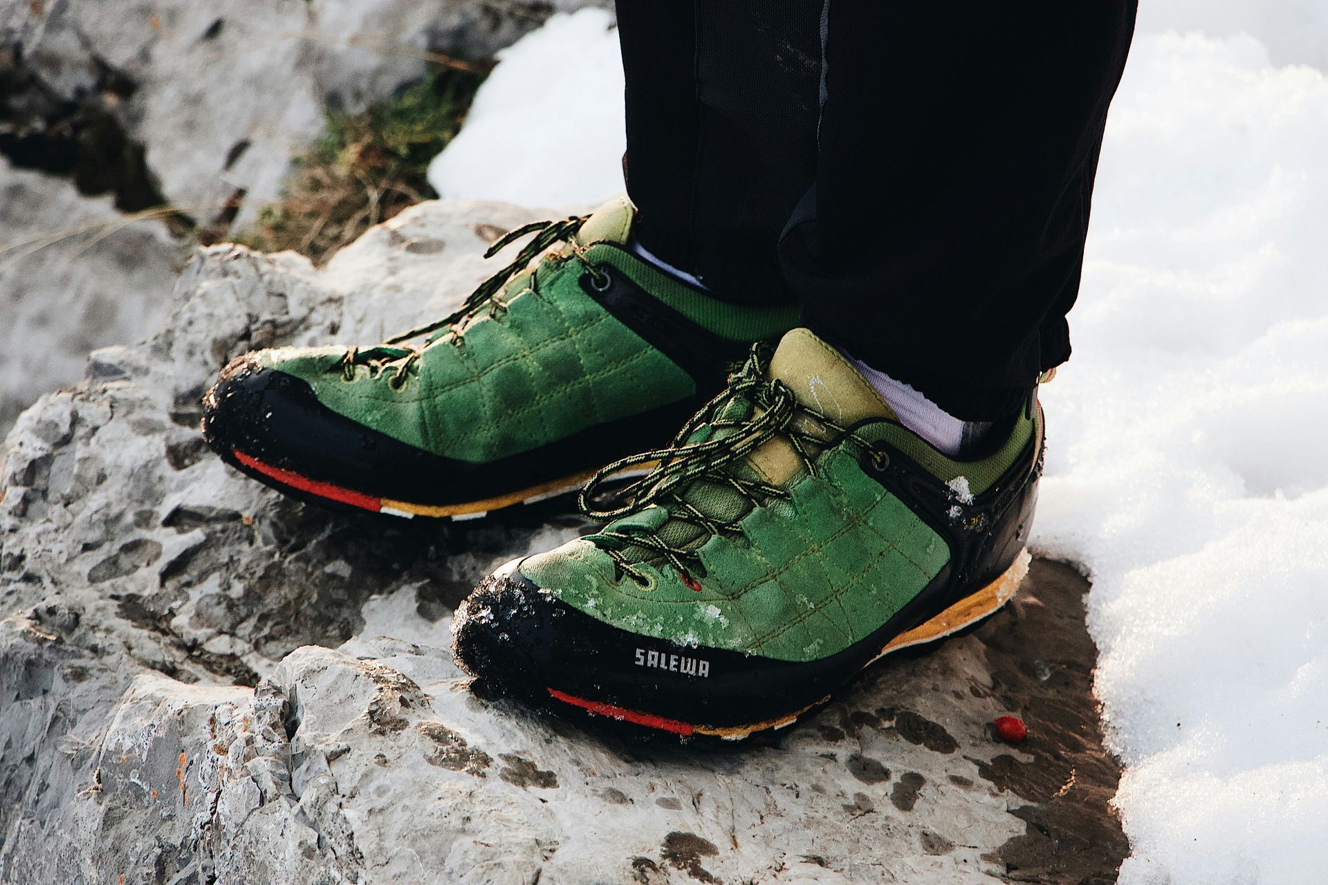 Proper rock climbing shoes standing on a rock with snow in the background