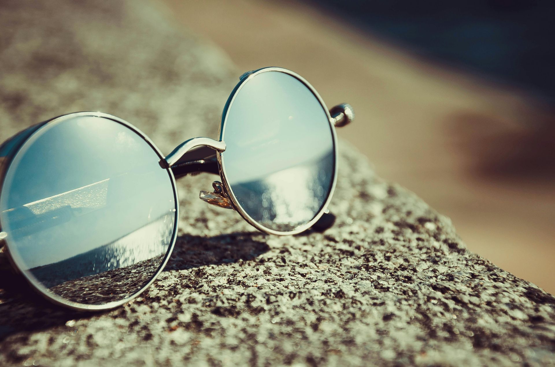 Sunglasses sitting on ledge with sun reflection in the lenses