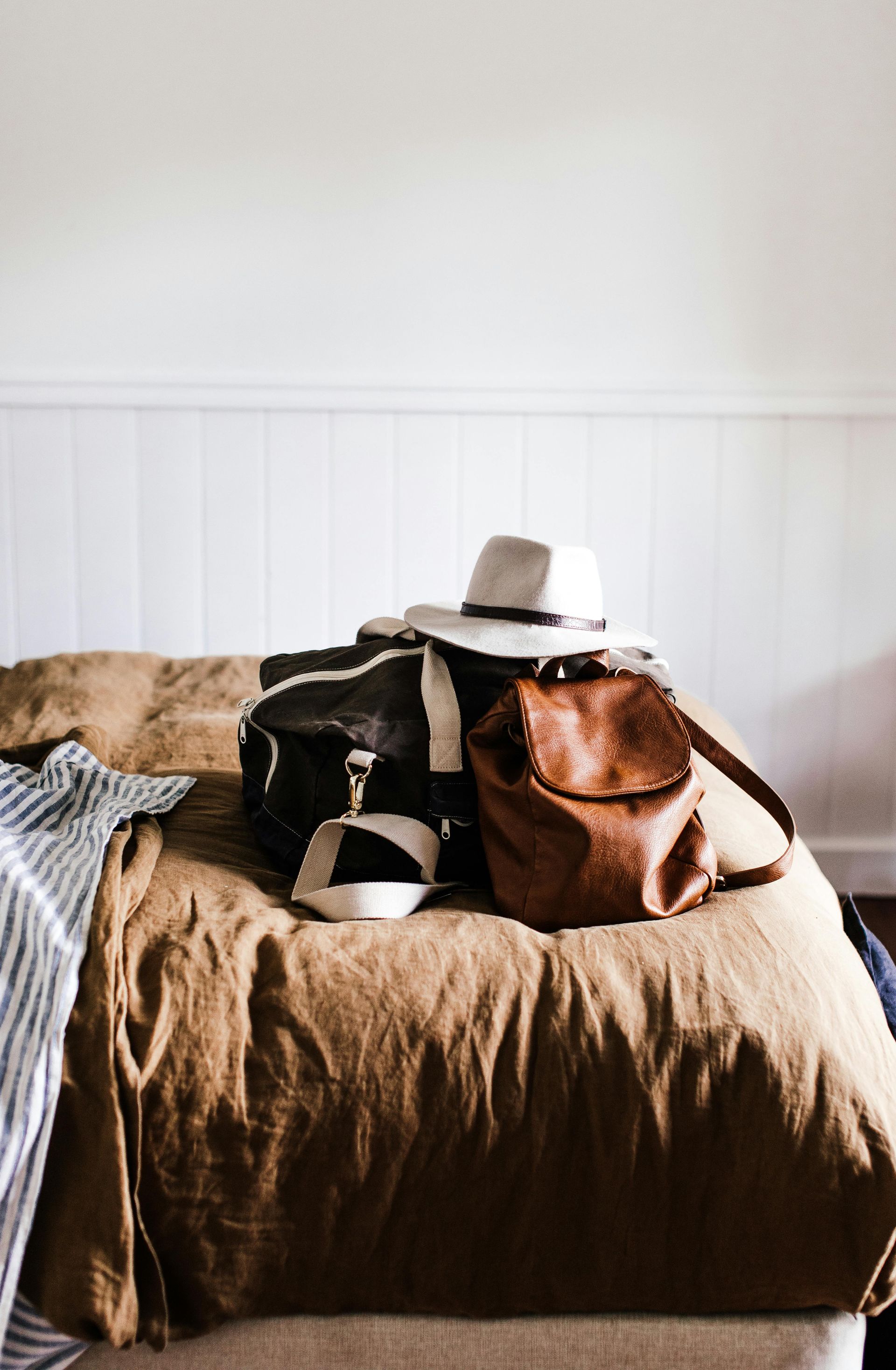 Packed bags on the bed of a vacation rental with hat on top