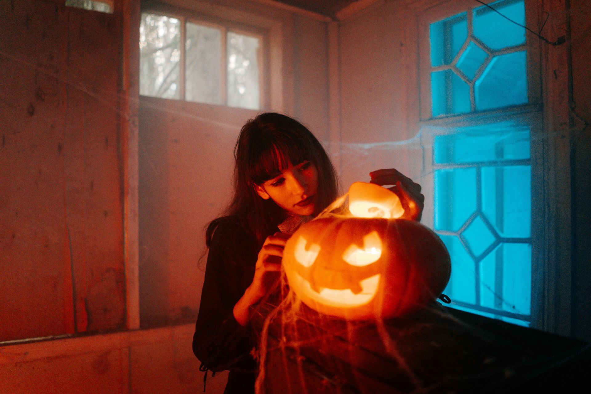 Woman admiring carved pumpkin in a dark spooky room