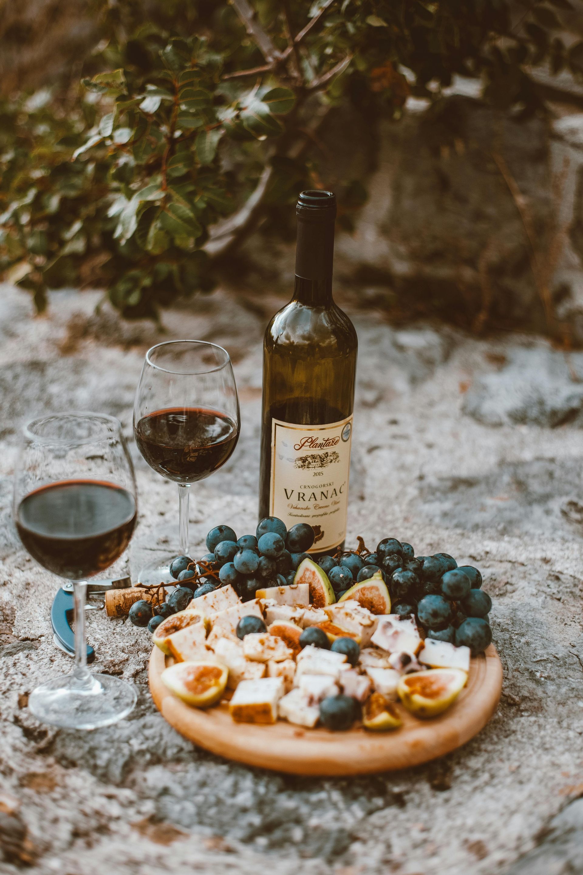 Bottle of win sitting on a granite table next to a cheeseboard