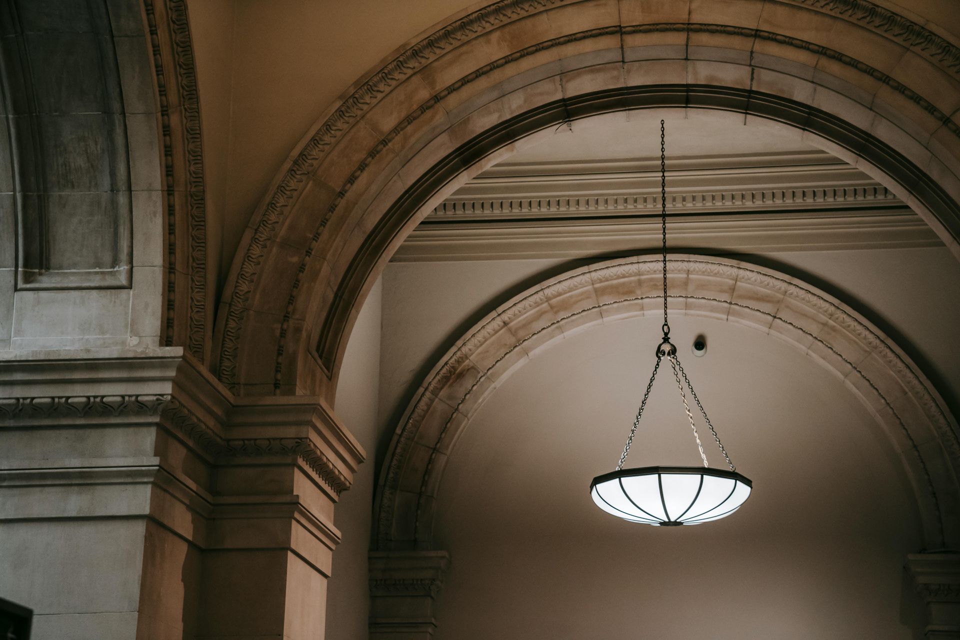 View of historic museum with detailed arches and light hanging from ceiling 