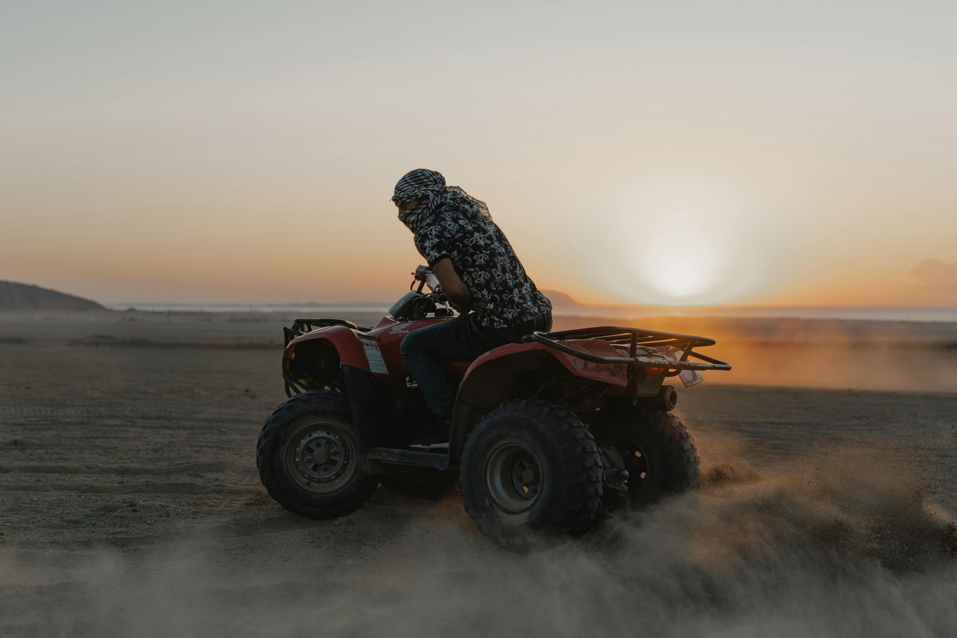 Person riding ATV on an open dirt field