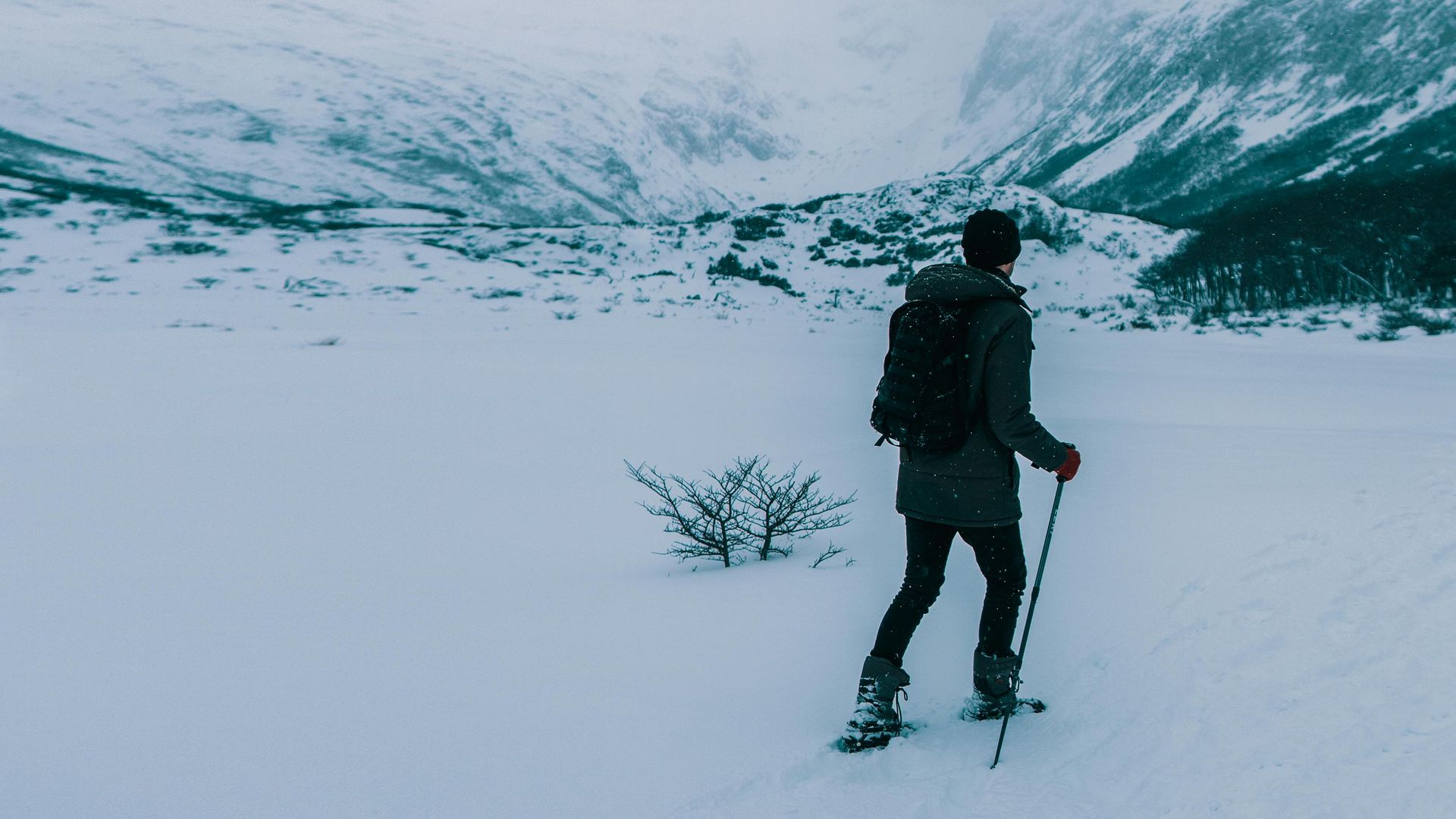 Person snowshoeing in a deep snowy mountain landscape