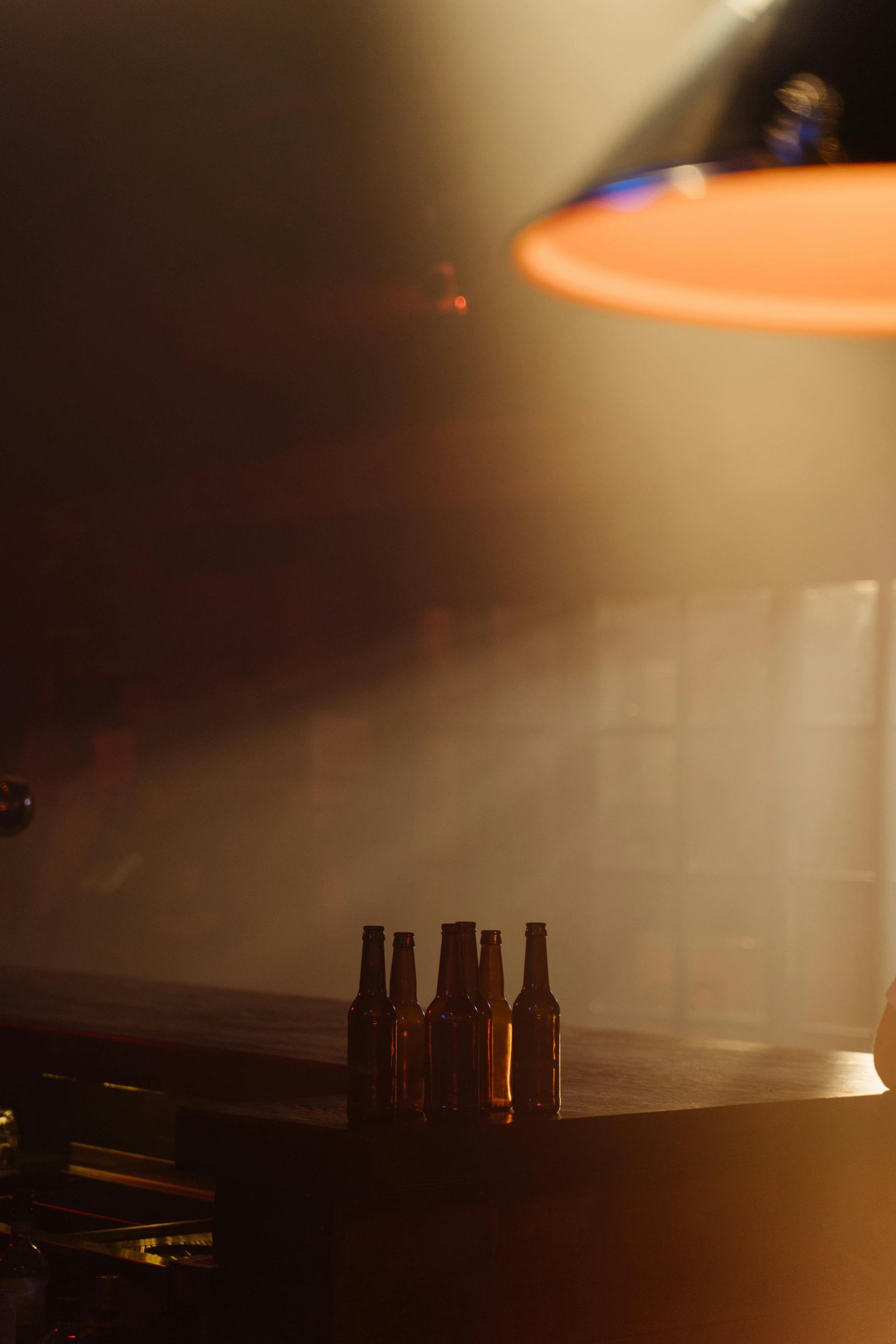 Brown beer bottles sitting on an empty table with golden streaks of light filling the room