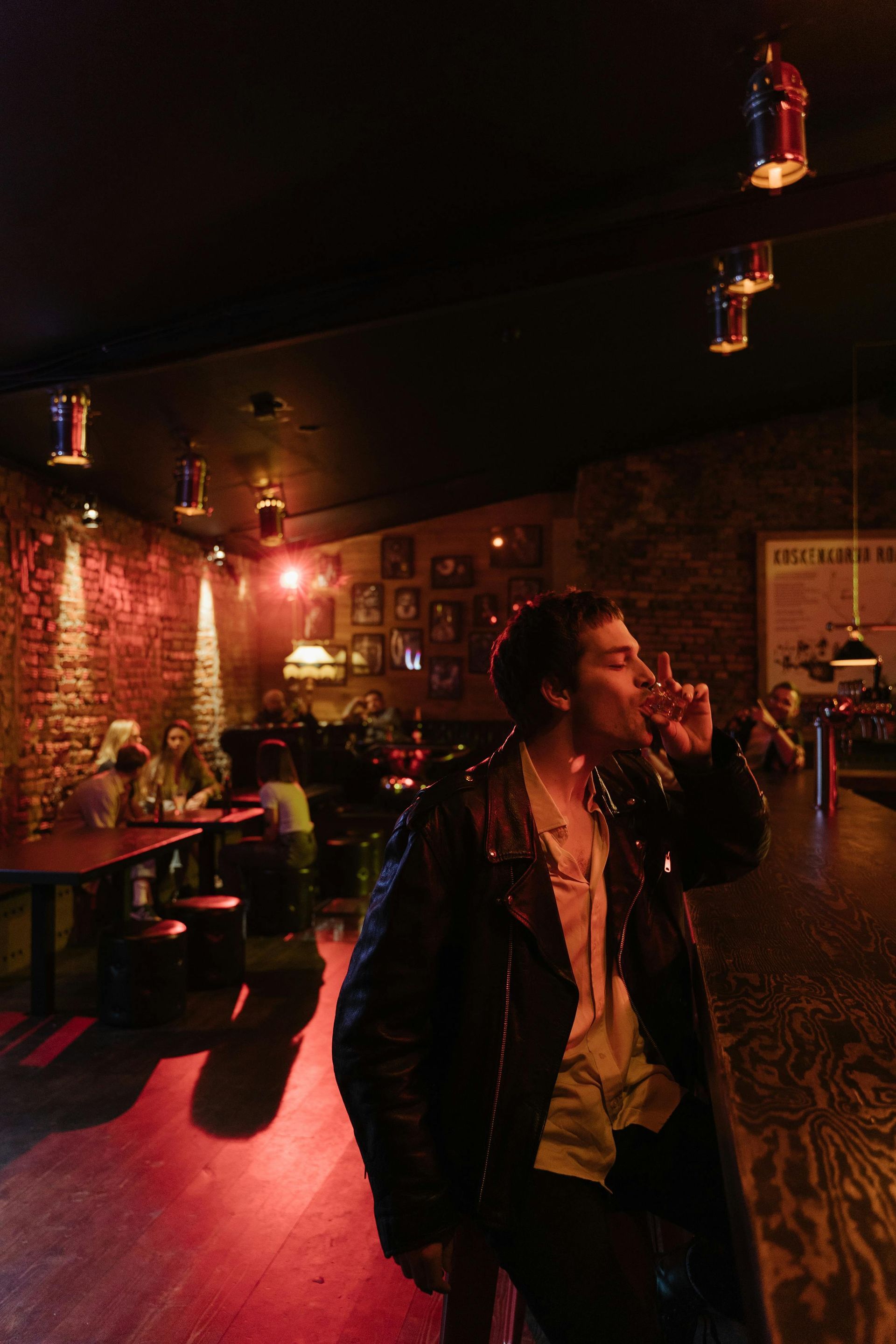 Man in a leather jacket enjoying drinks at a roadhouse bar with live music nearby