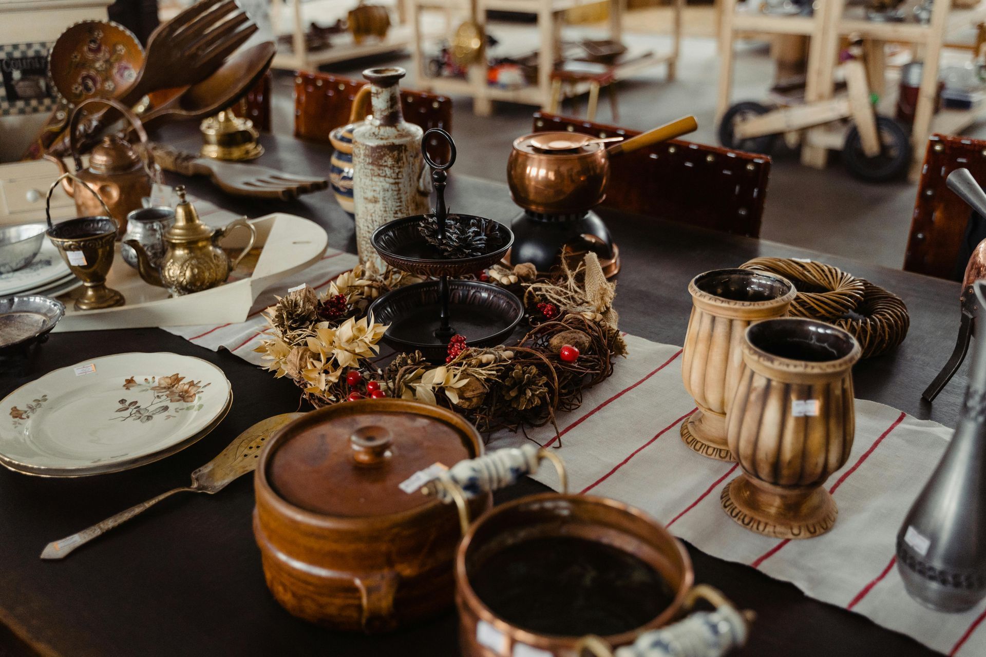 Table set with antique dishes, pottery, and a festive wreath