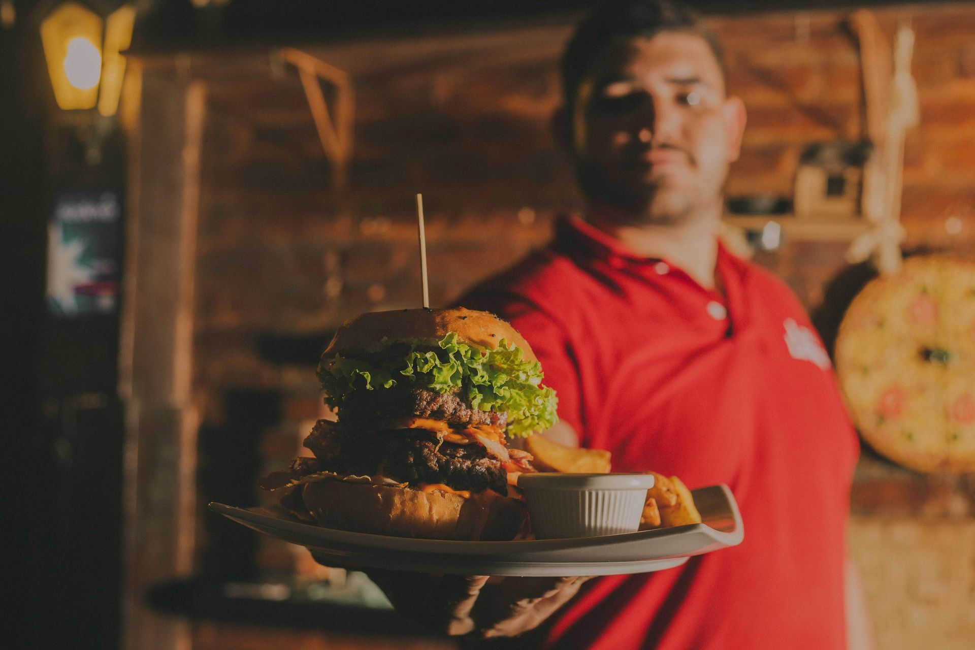 Waiter delivering a large, stacked burger to a table at a family restaurant
