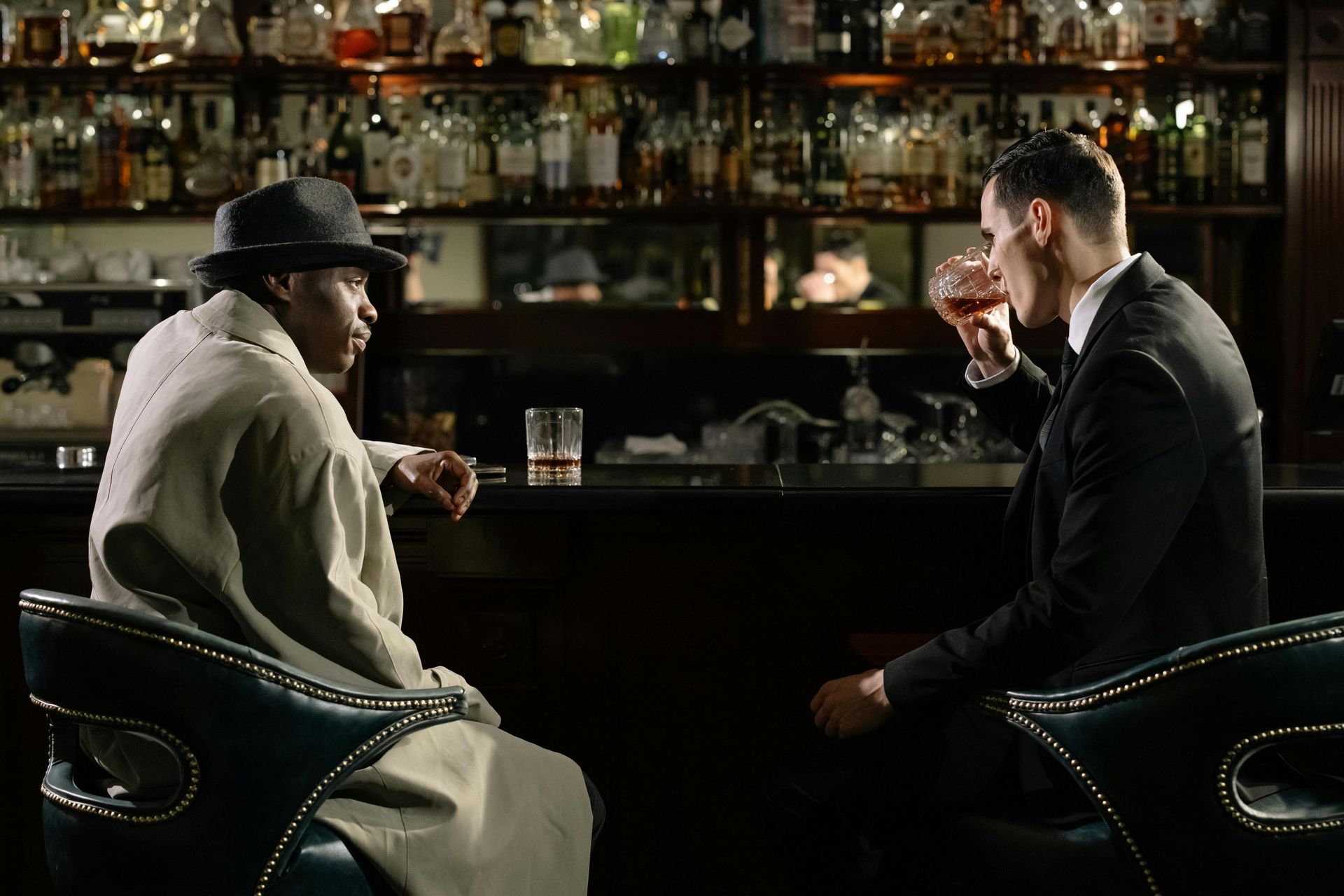 Two gentlemen sitting at saloon, talking and drinking together