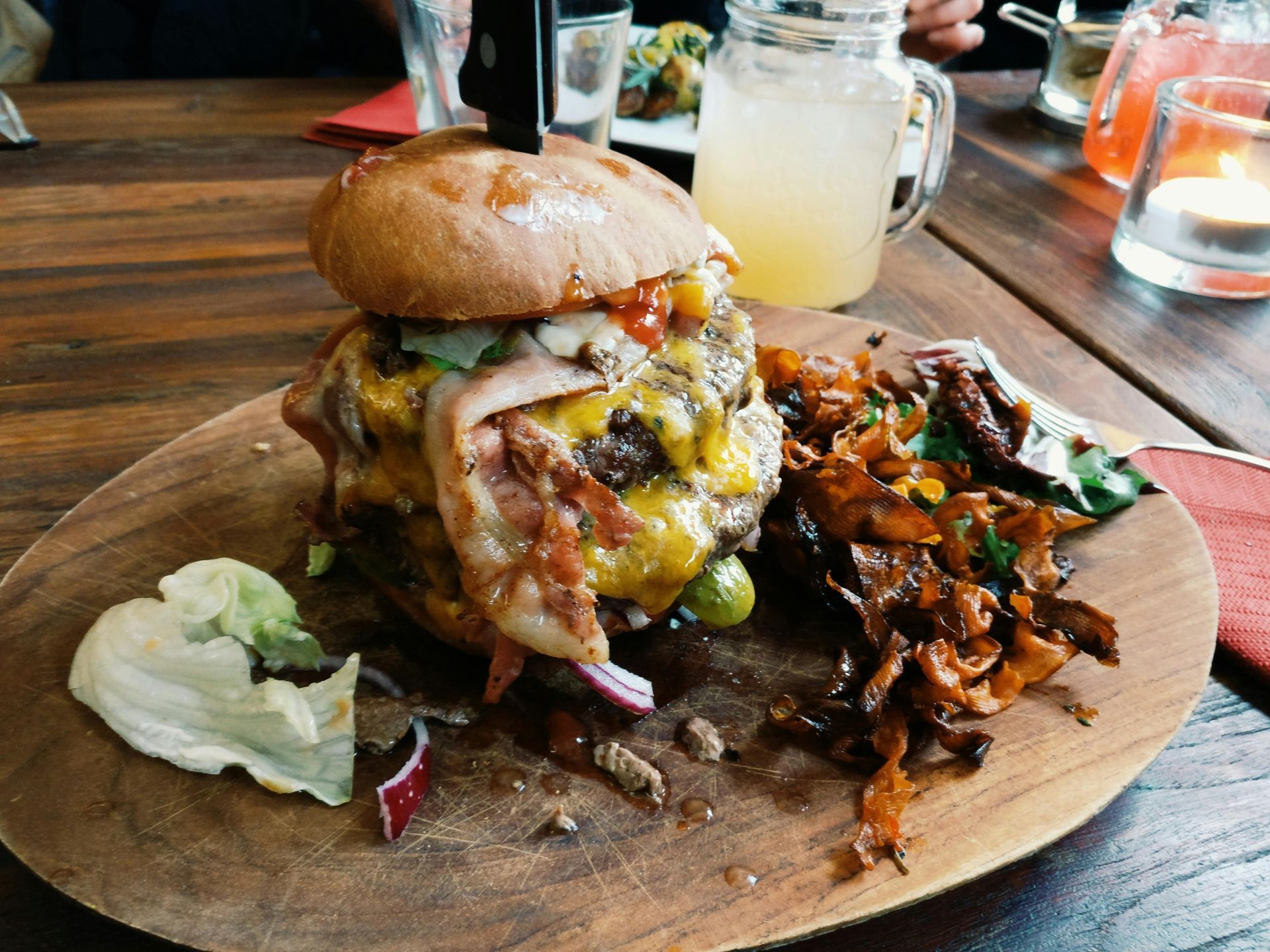 Large, stuffed burger on plate with drinks at restaurant 