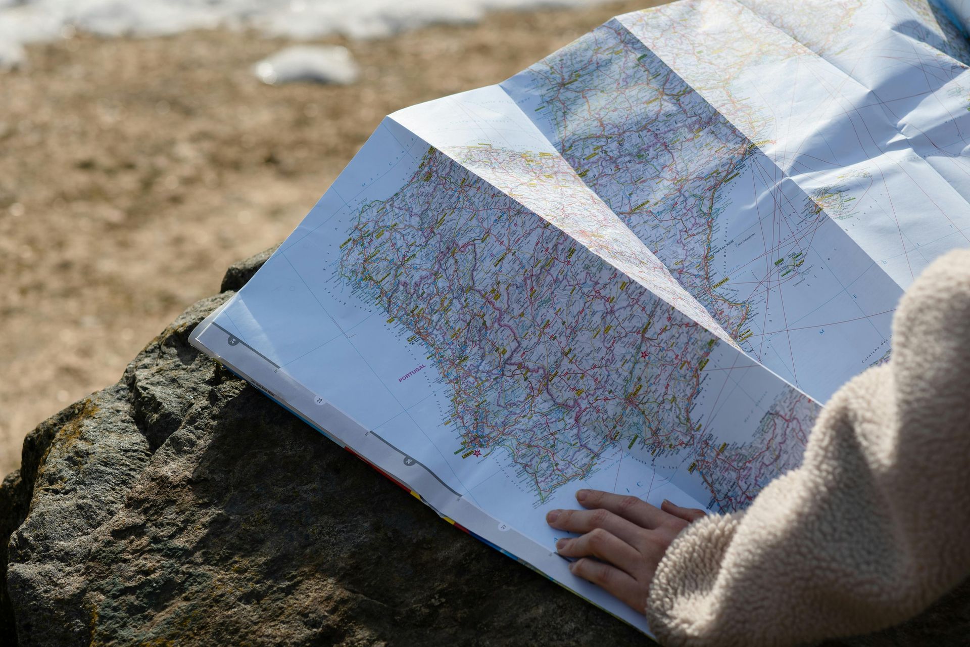 Person looking at map while sitting on rock 