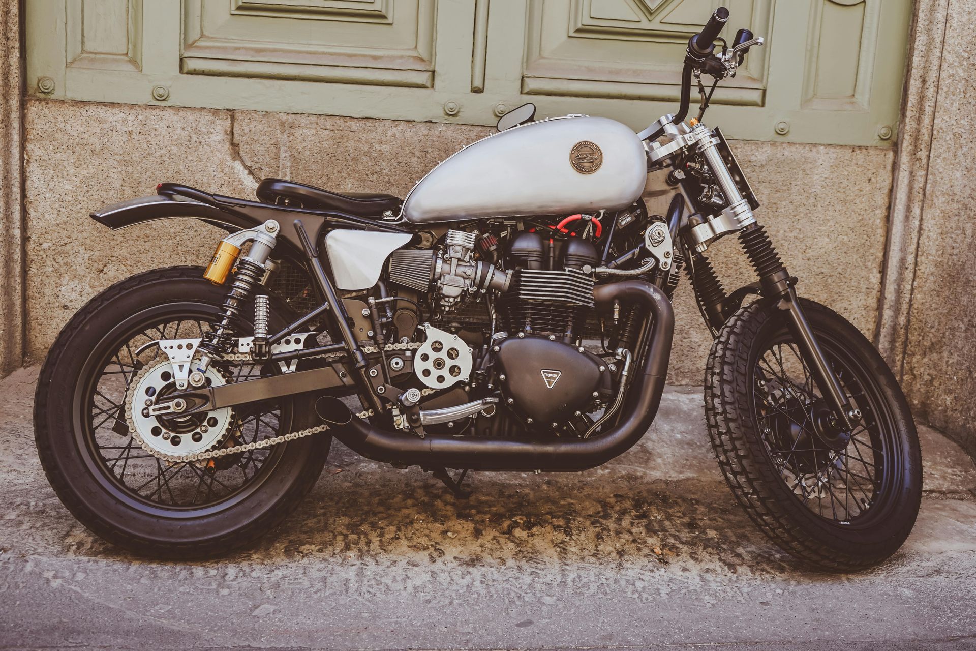 Motorcycle propped up against a wall off of a street