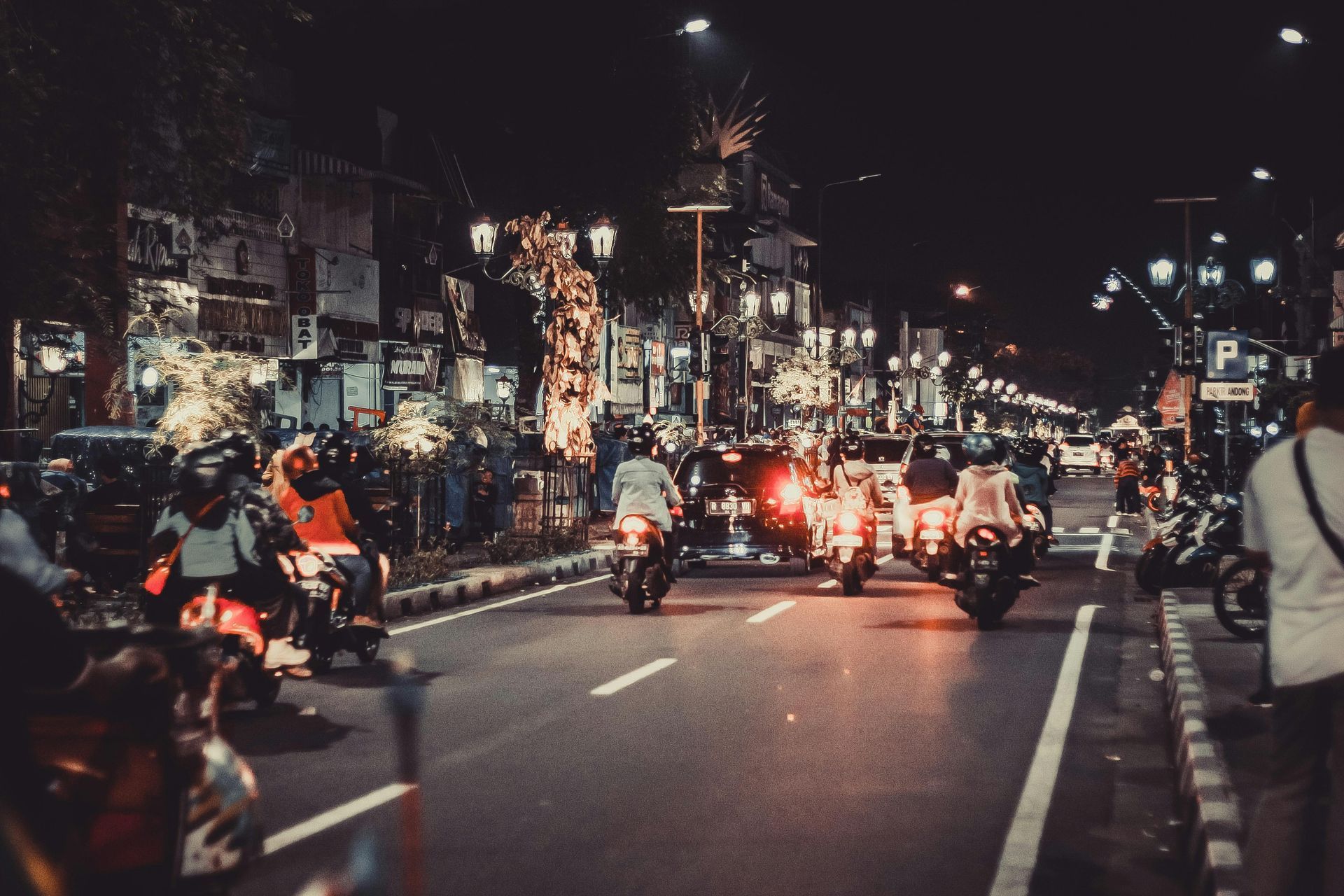 Group of people riding motorcycles at night throughout a town