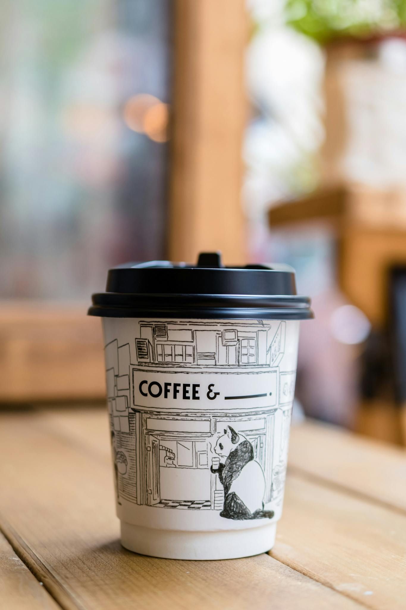 A fresh cup of coffee in a paper cup on a wooden table