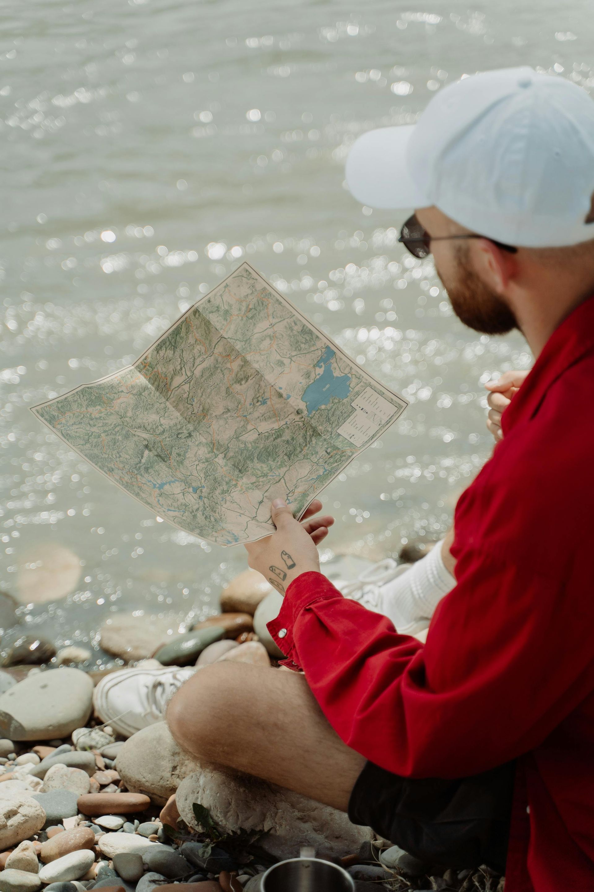 Man planning a kayak route with a map near a riverbed