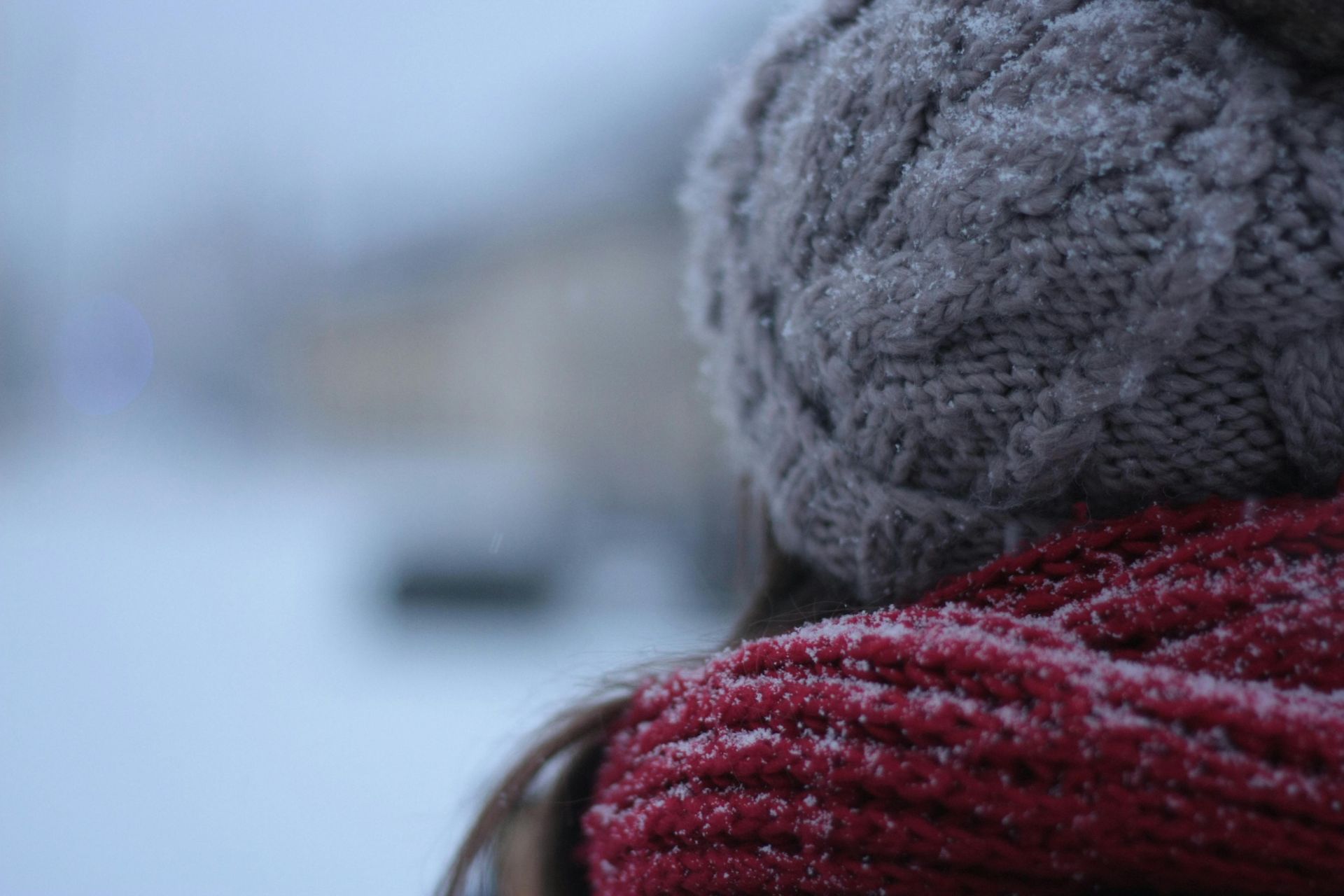 Back view of woman with winter hat and scarf with blurred background