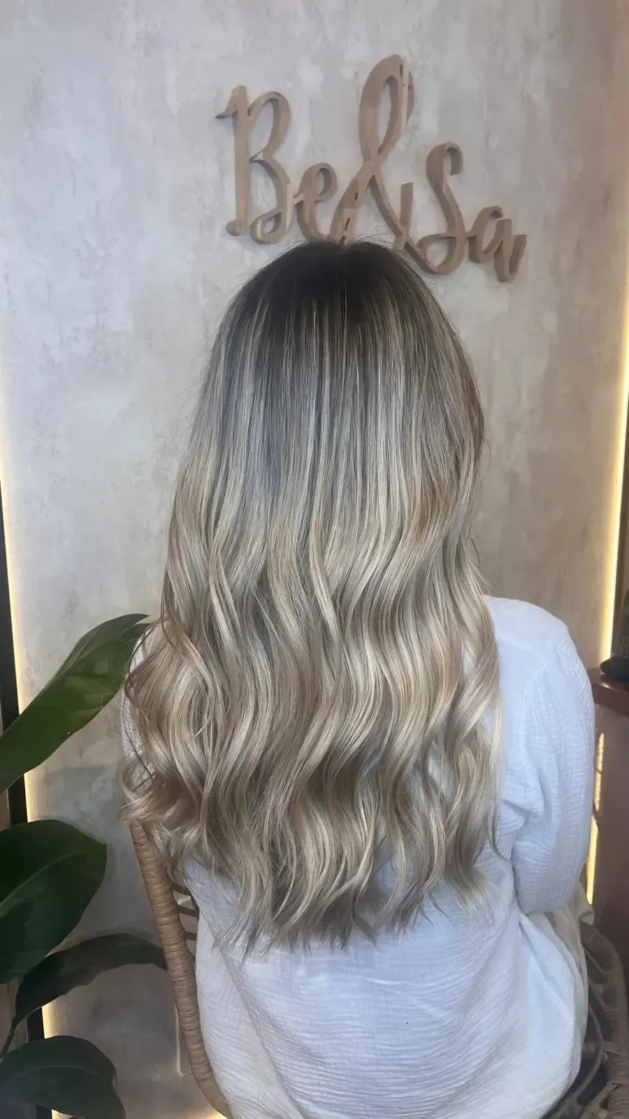 En un salón de belleza, un estilista utiliza tijeras de entresacar y un peine para recortar el cabello castaño con mechas.