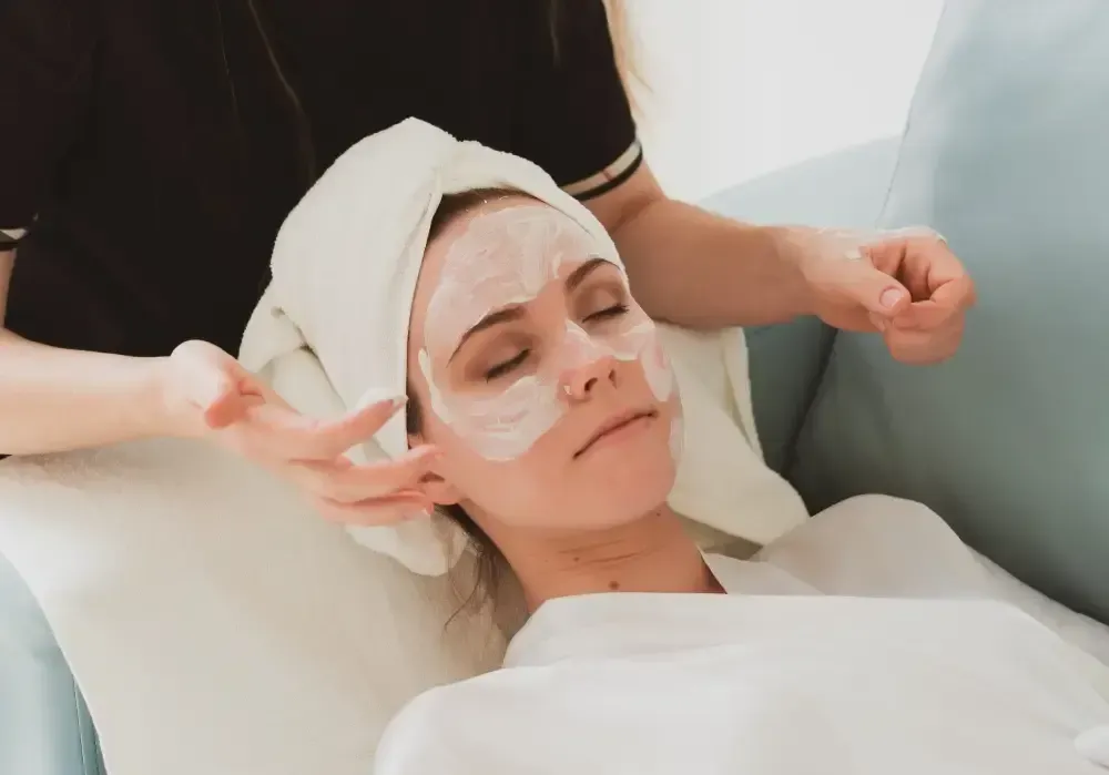 Vista trasera de una persona con cabello rubio con mechas, peinado en una cresta trenzada que termina en una coleta baja.