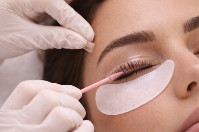 En un salón de belleza, un estilista utiliza tijeras de entresacar y un peine para recortar el cabello castaño con mechas.