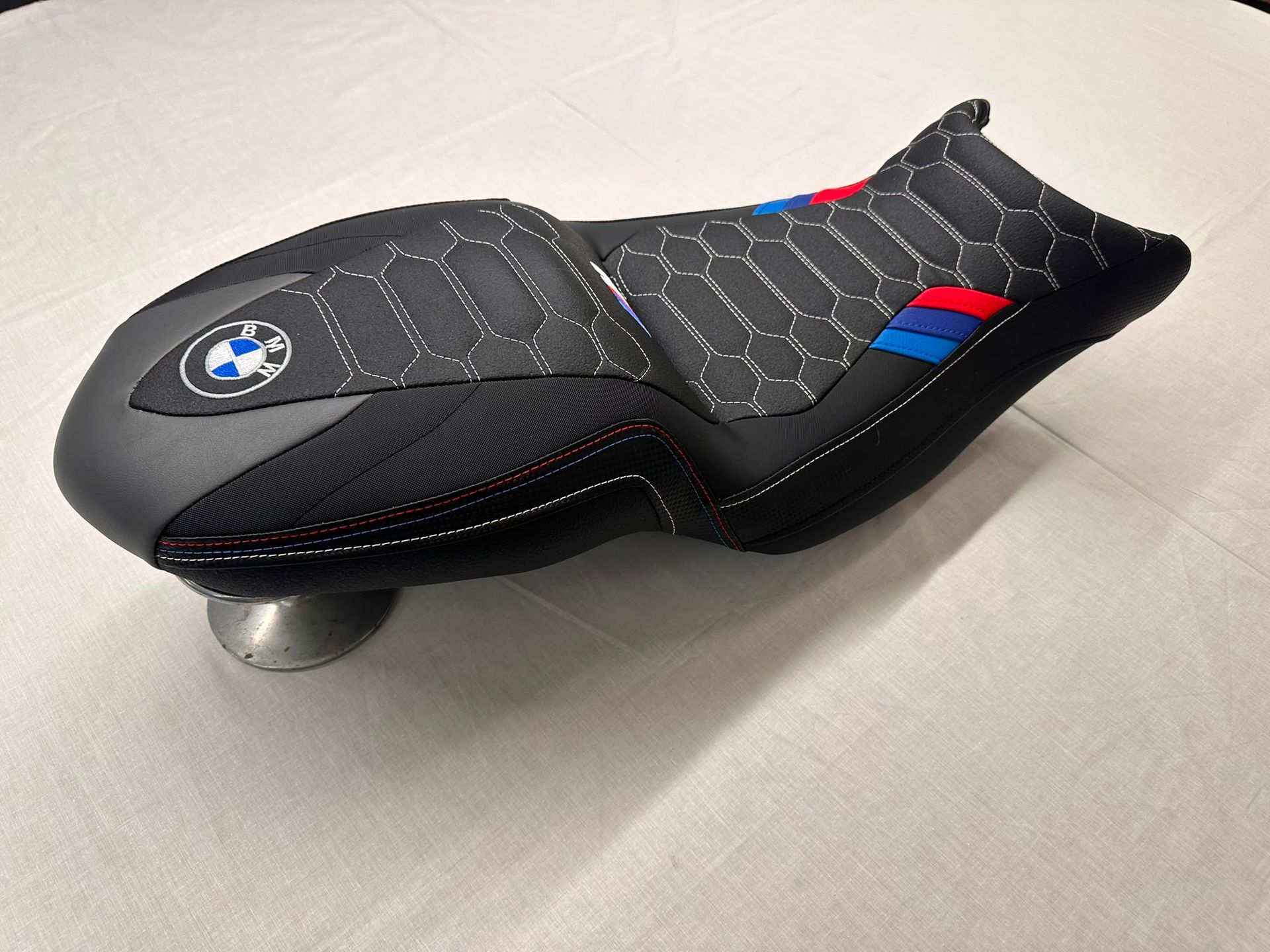 Sillín de bicicleta negro de BMW con detalles en rojo y azul sobre una superficie clara