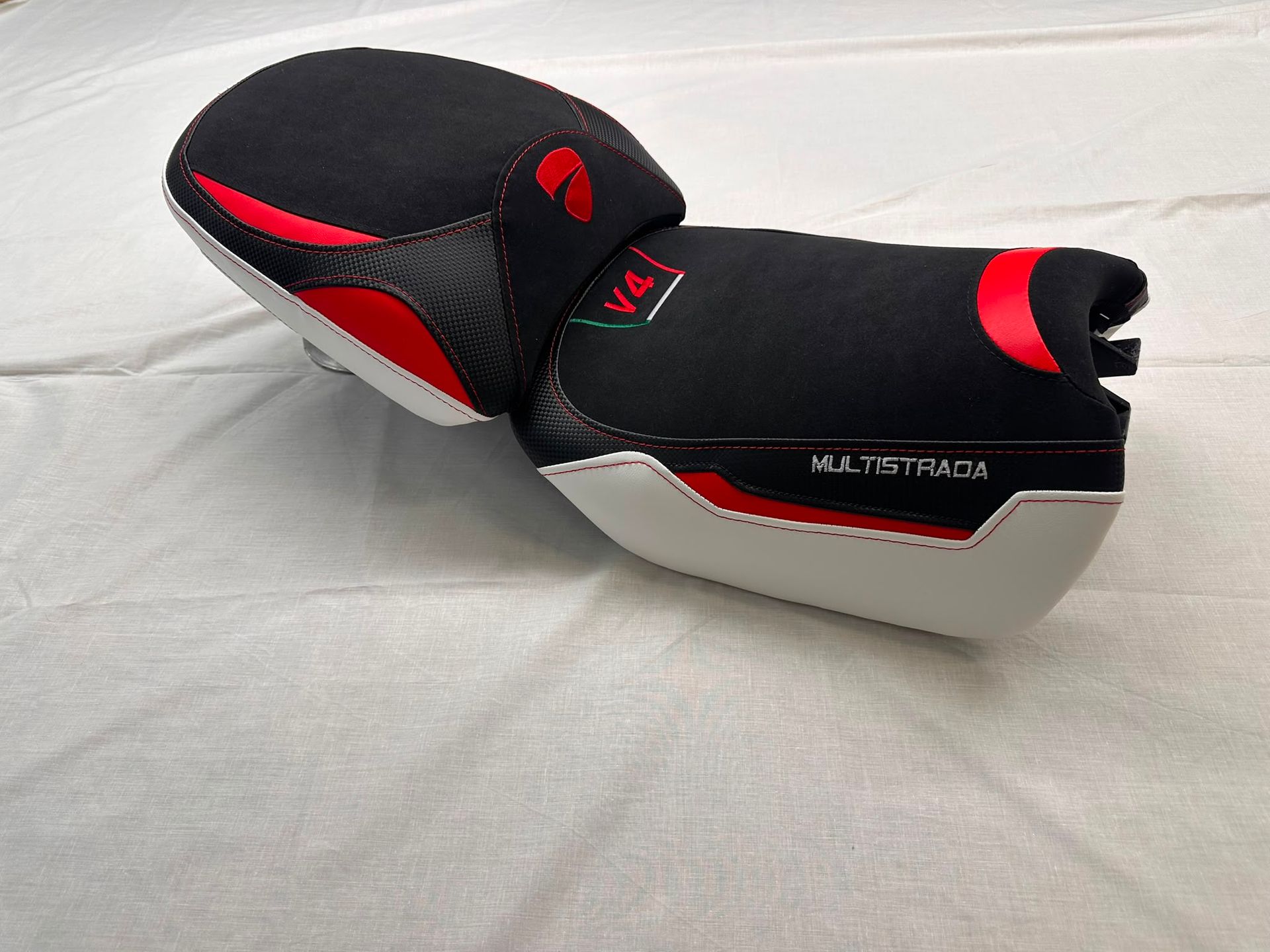 Asiento de moto negro y rojo sobre un fondo de tela gris claro