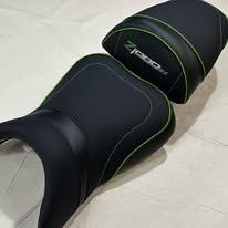 Un juego de asientos para piloto y pasajero para motocicleta Kawasaki Z1000SX, con tapicería negra, ribetes verdes y bordados.