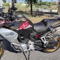 Una motocicleta BMW GS de color plateado y marrón estacionada sobre una superficie pavimentada durante el día.