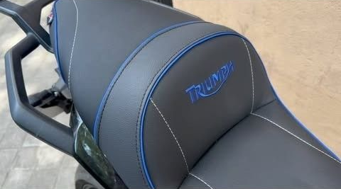 Asiento de motocicleta Triumph negro con ribetes azules y bordado del logotipo de Triumph en azul.